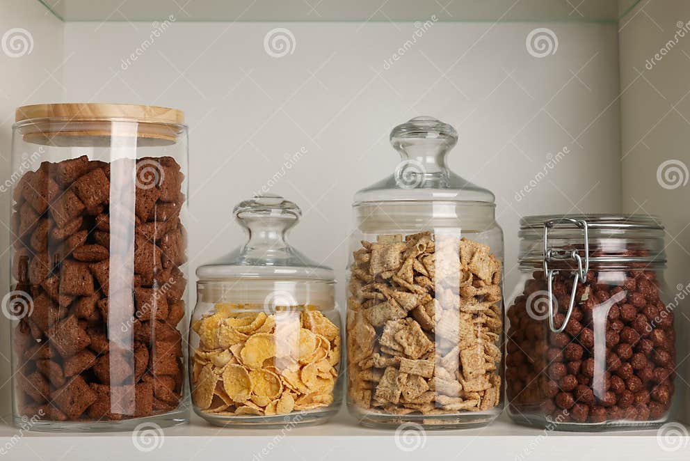 Glass Containers with Different Breakfast Cereals on Shelf Stock Photo