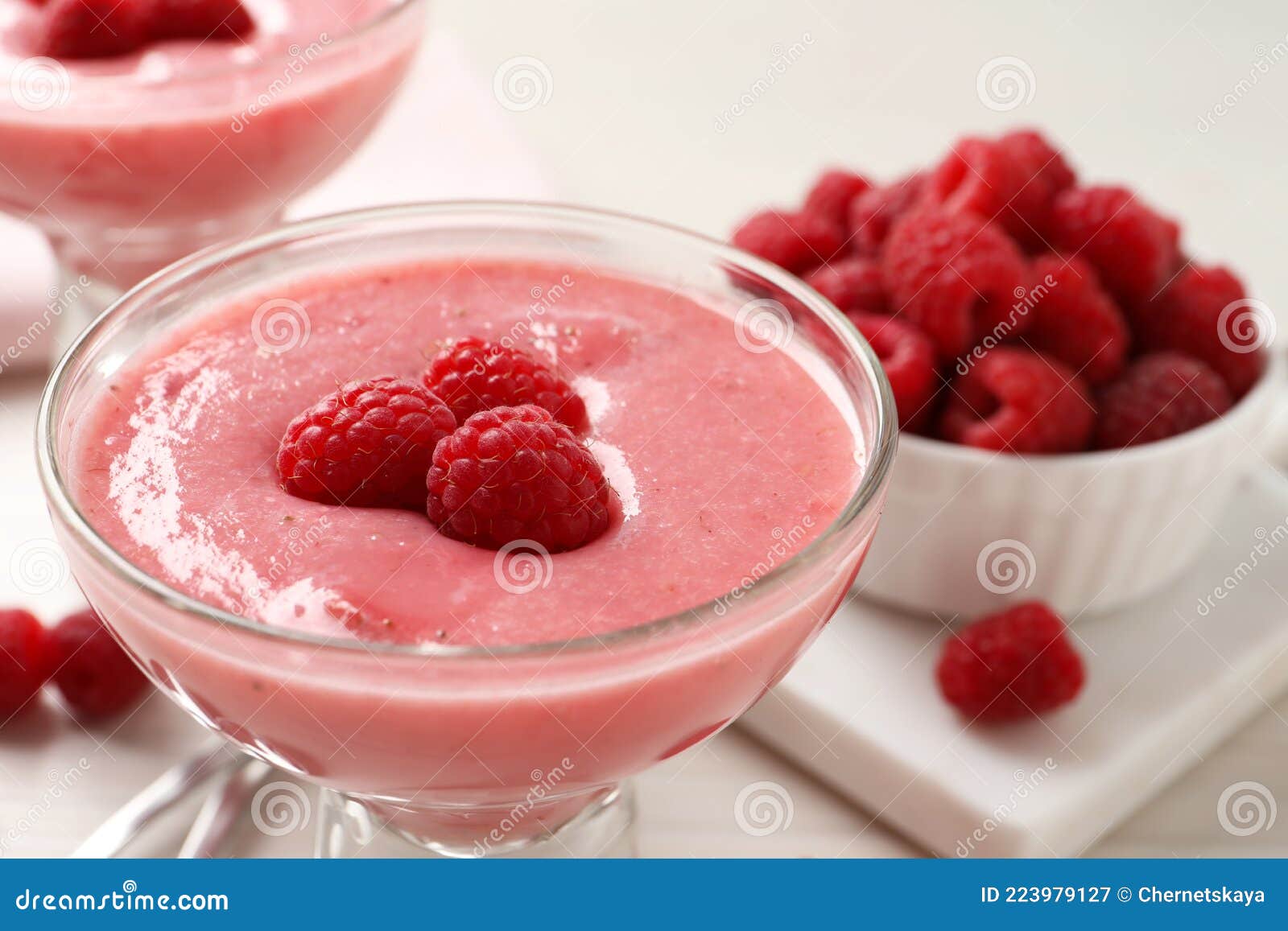 glass of delicious raspberry mousse on table, closeup view