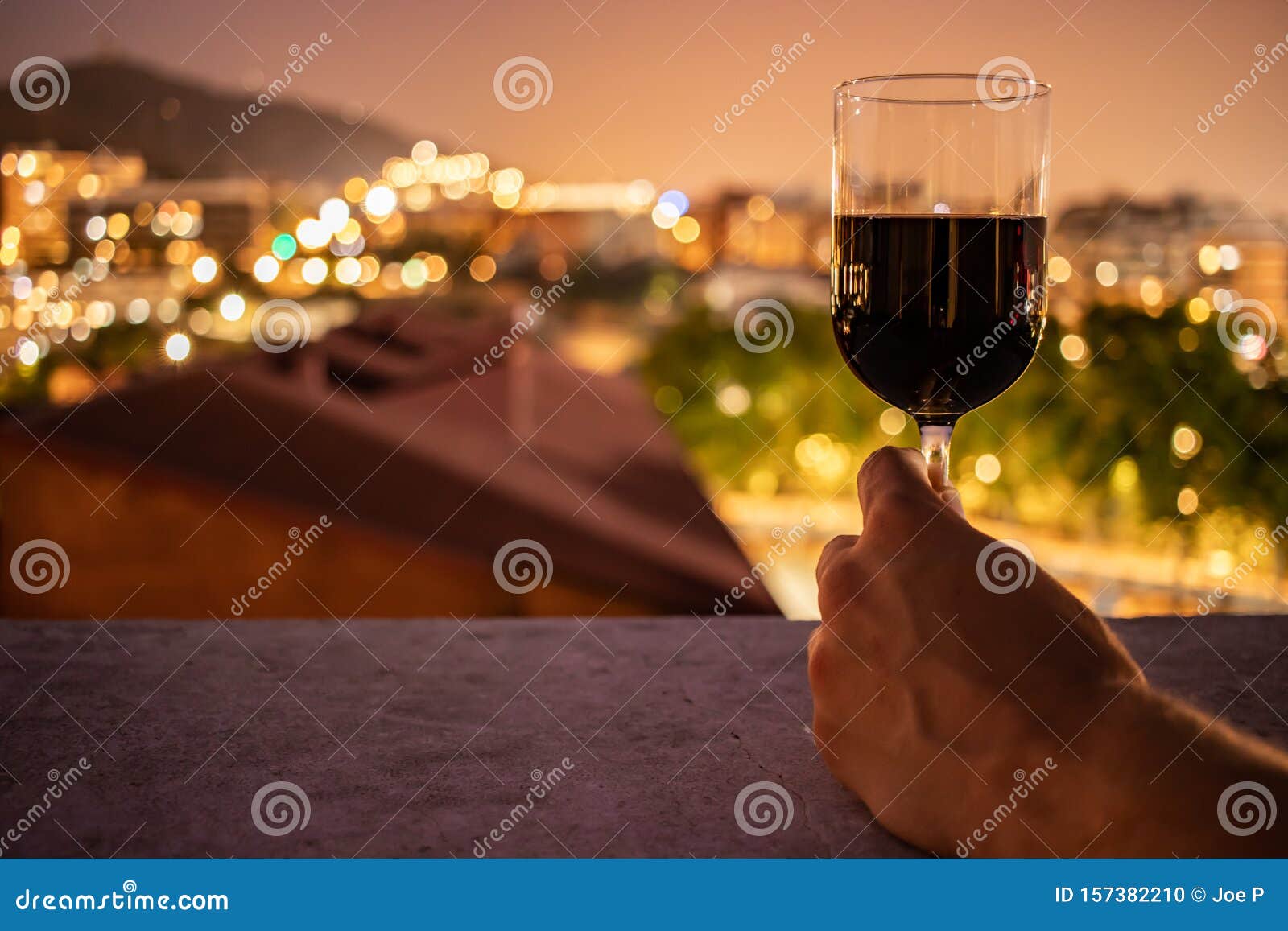 glass full of red wine held by a young male hand