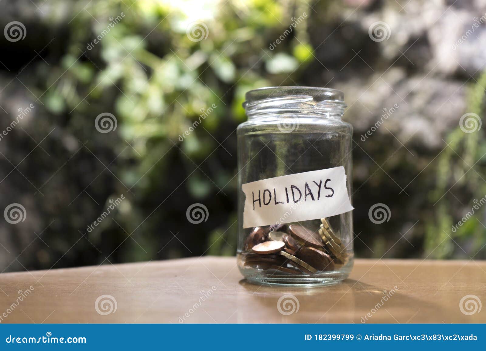 a glass jar with coins inside and a `vacaciones` tag on a wooden. un bote de cristal con monedas dentro, tiene una etiqueta que po