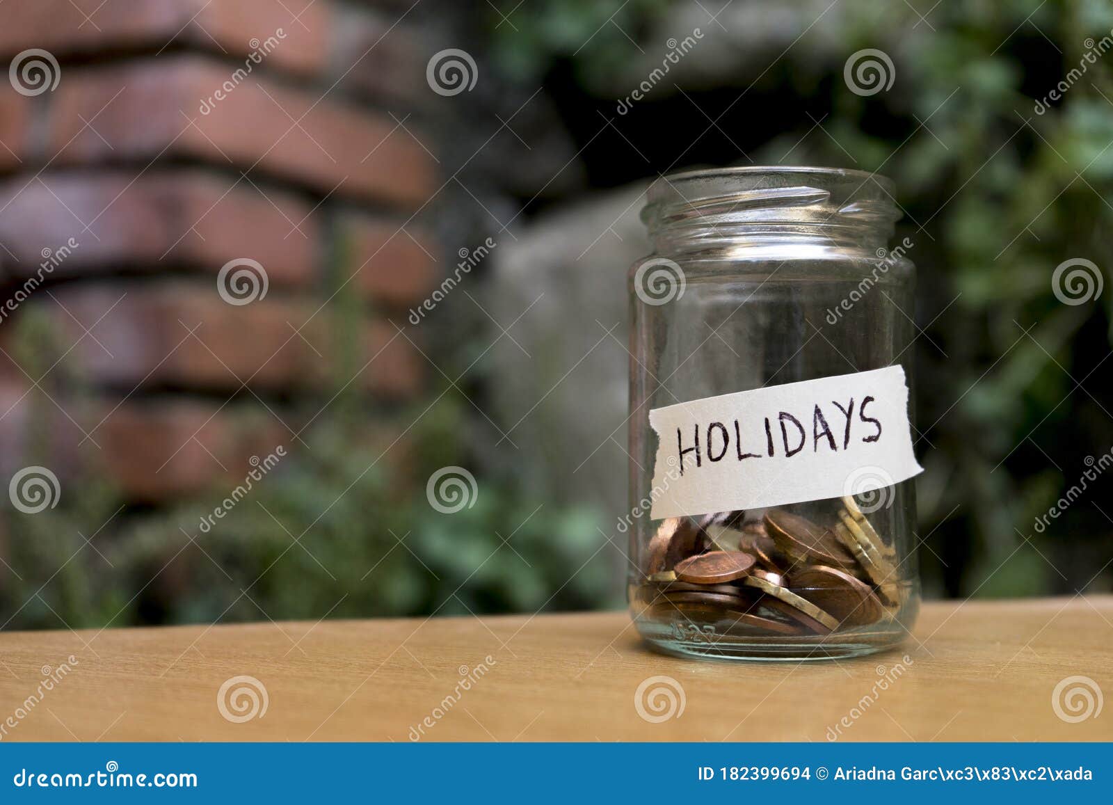 a glass jar with coins inside and a `vacaciones` tag on a wooden. un bote de cristal con monedas dentro, tiene una etiqueta que po