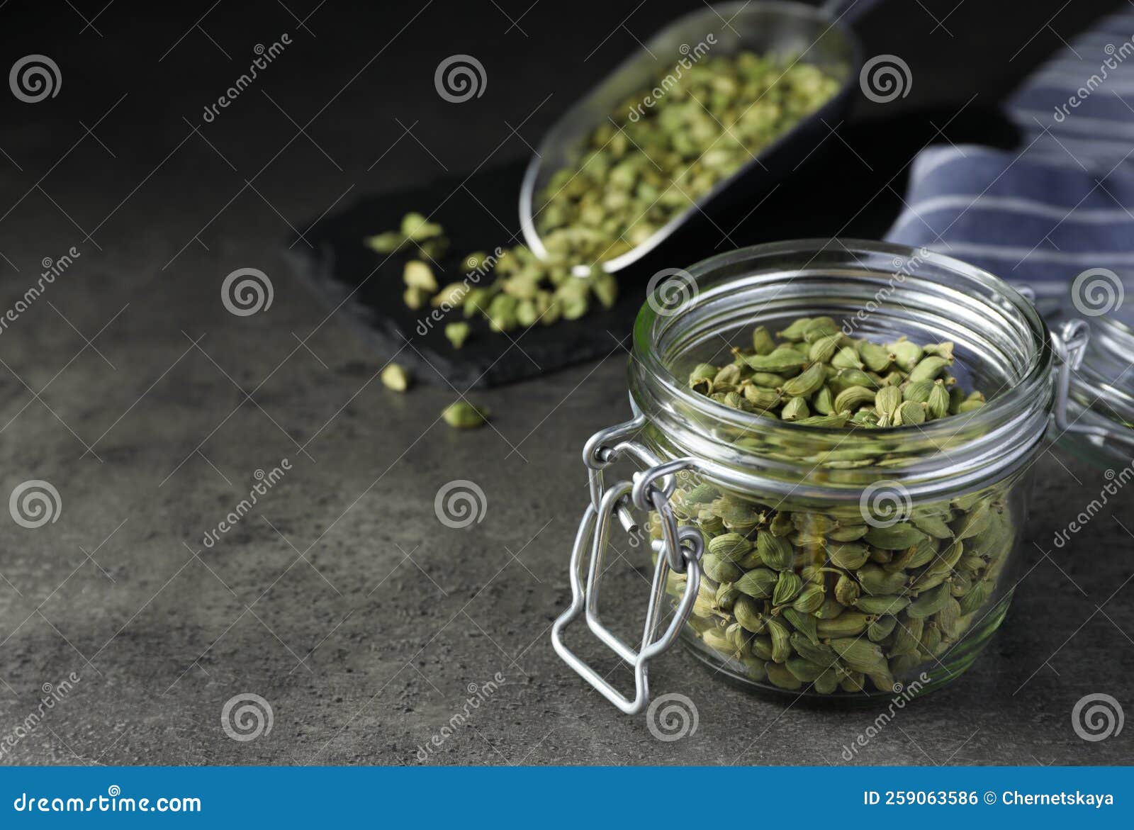 Glass Jar with Dry Cardamom Pods on Dark Grey Table, Space for Text