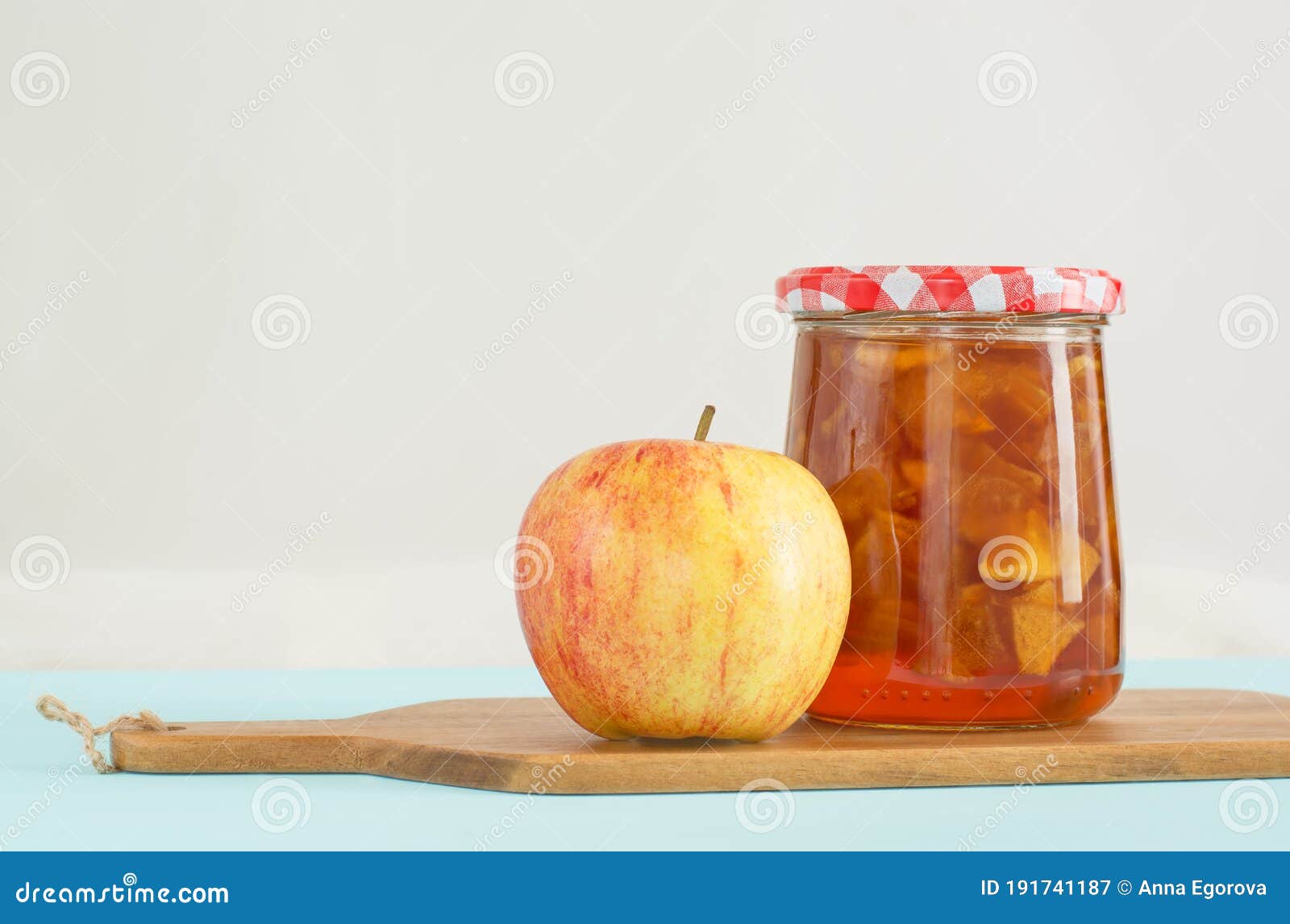 Glass Jar of Homemade Apple Jam with Checkered Lid and Apple Stock