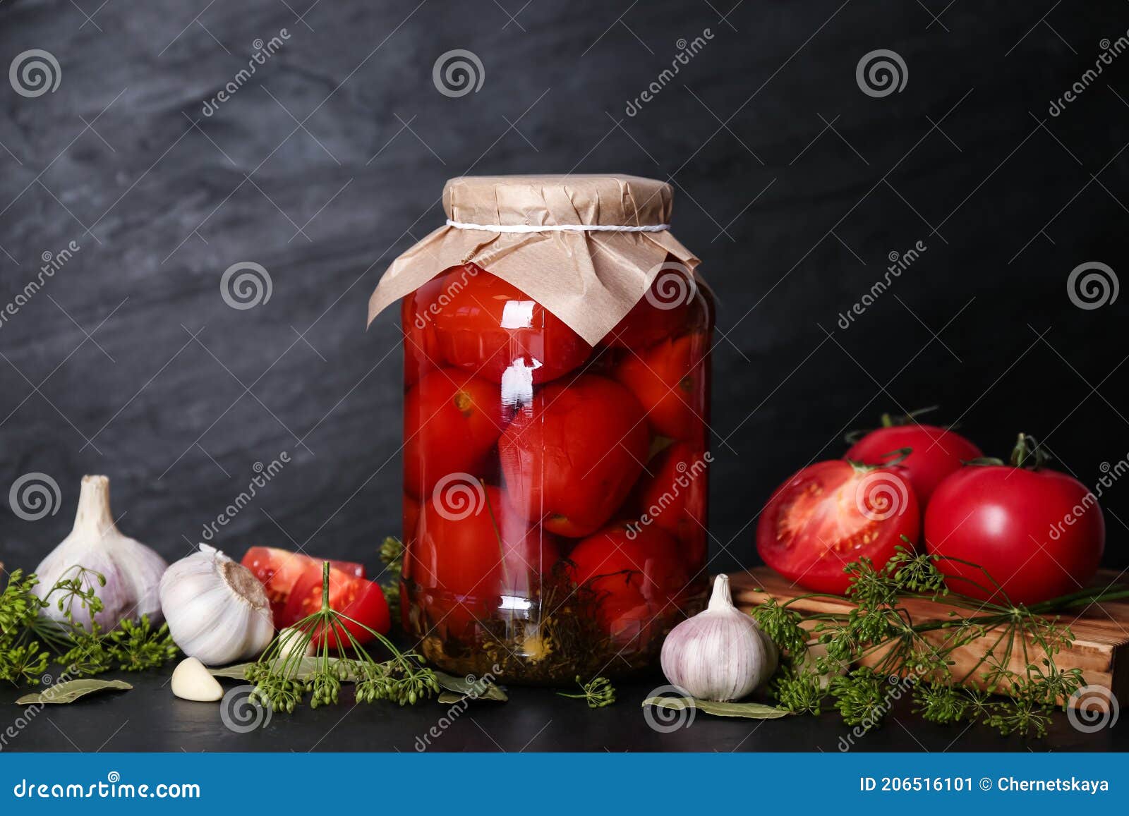 Glass Jar of Pickled Tomatoes and Ingredients on Black Table Stock