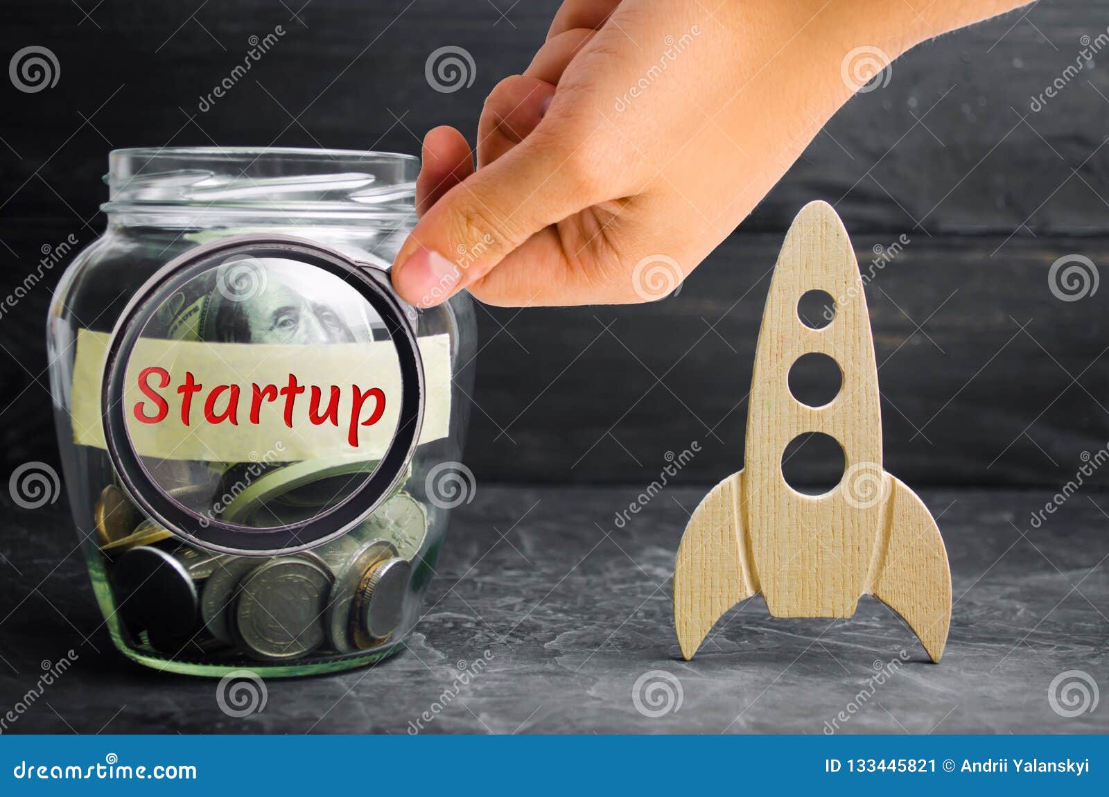 glass jar, rocket and the word `startup`. the concept of raising funds for a startup. charitable contributions to translate ideas