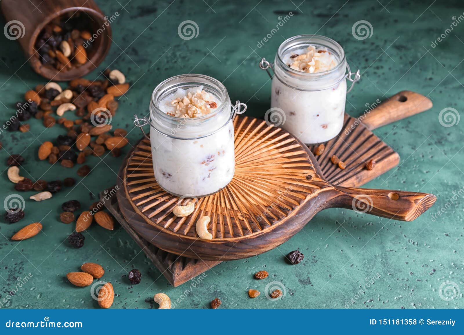 Glass Jars with Delicious Rice Pudding and Nuts on Green Table Stock