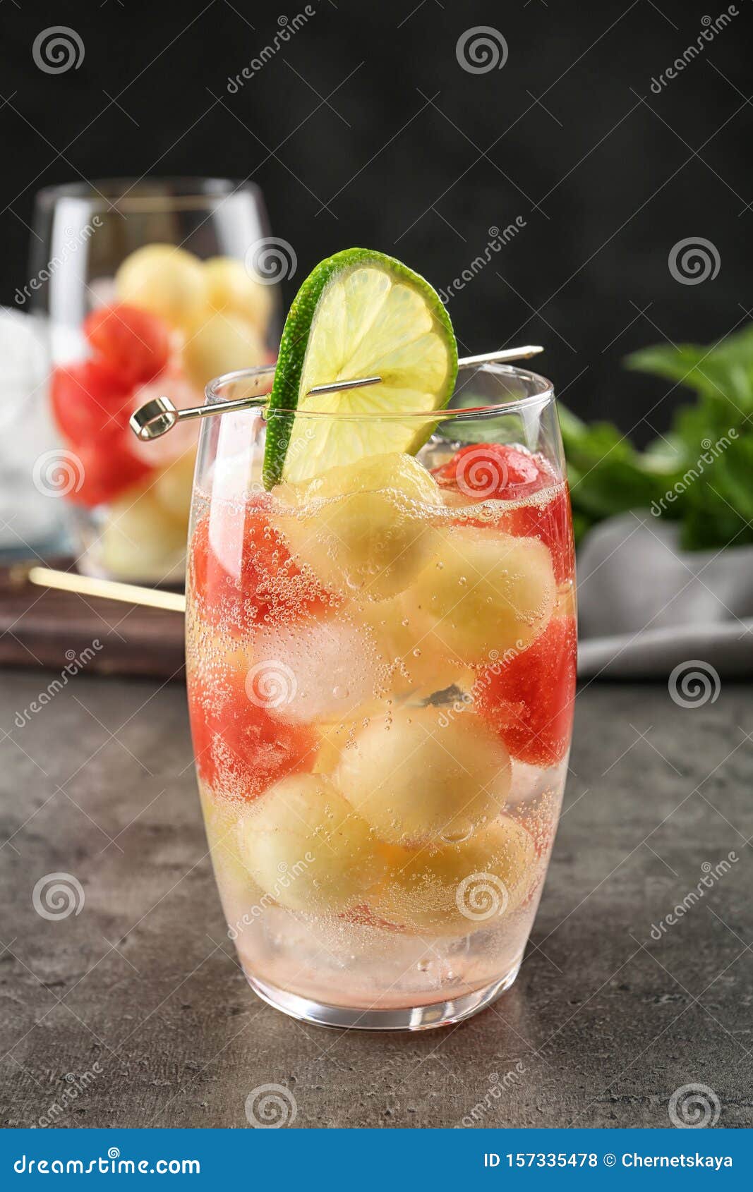 Glass of Melon and Watermelon Ball Cocktail with Lime on Table Stock