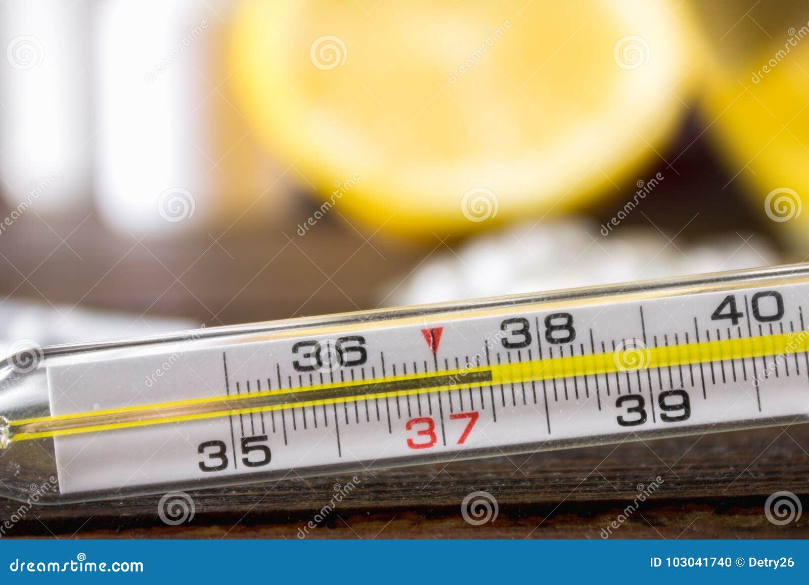glass mercury thermometer with a high temperature of 37.5 against the background of medicines, lemon, tea, folk remedies, tablets,
