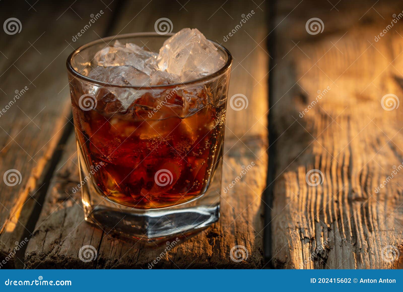 Glass of Old Whiskey with Ice Cubes on Wooden Background. Concept