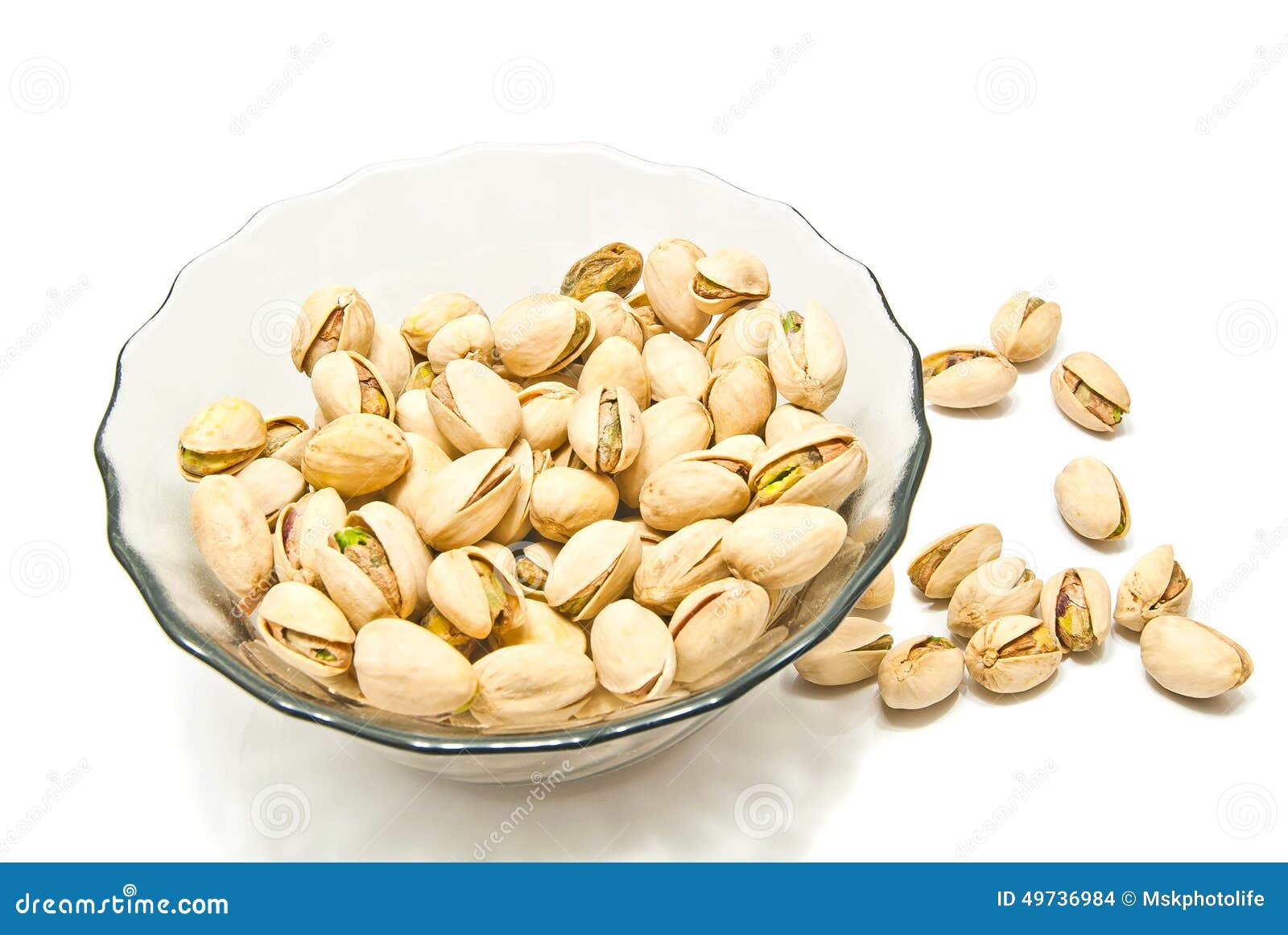 glass plate with tasty pistachios on white