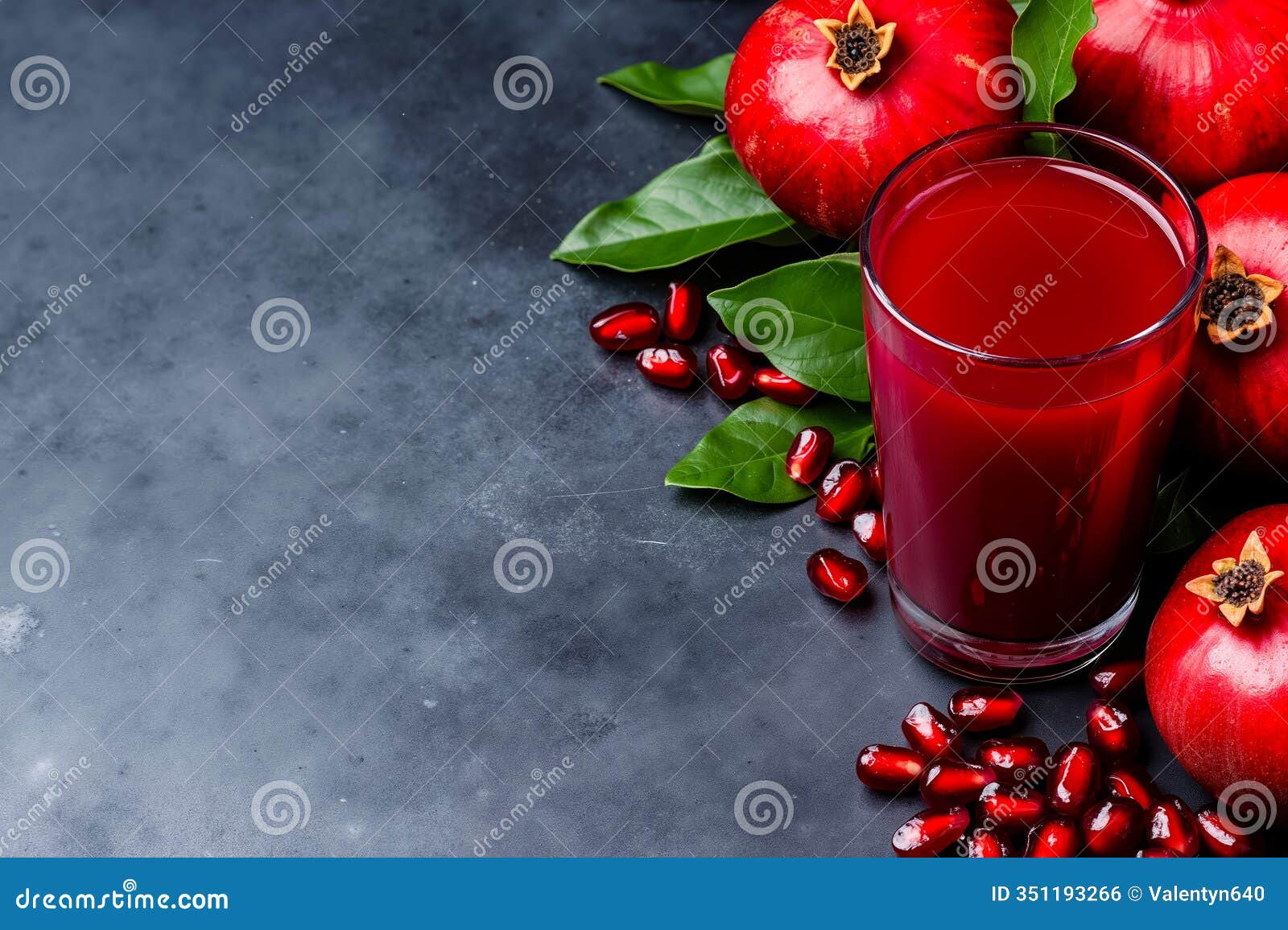 a glass of pomegranate juice next to some pomegrates on a table