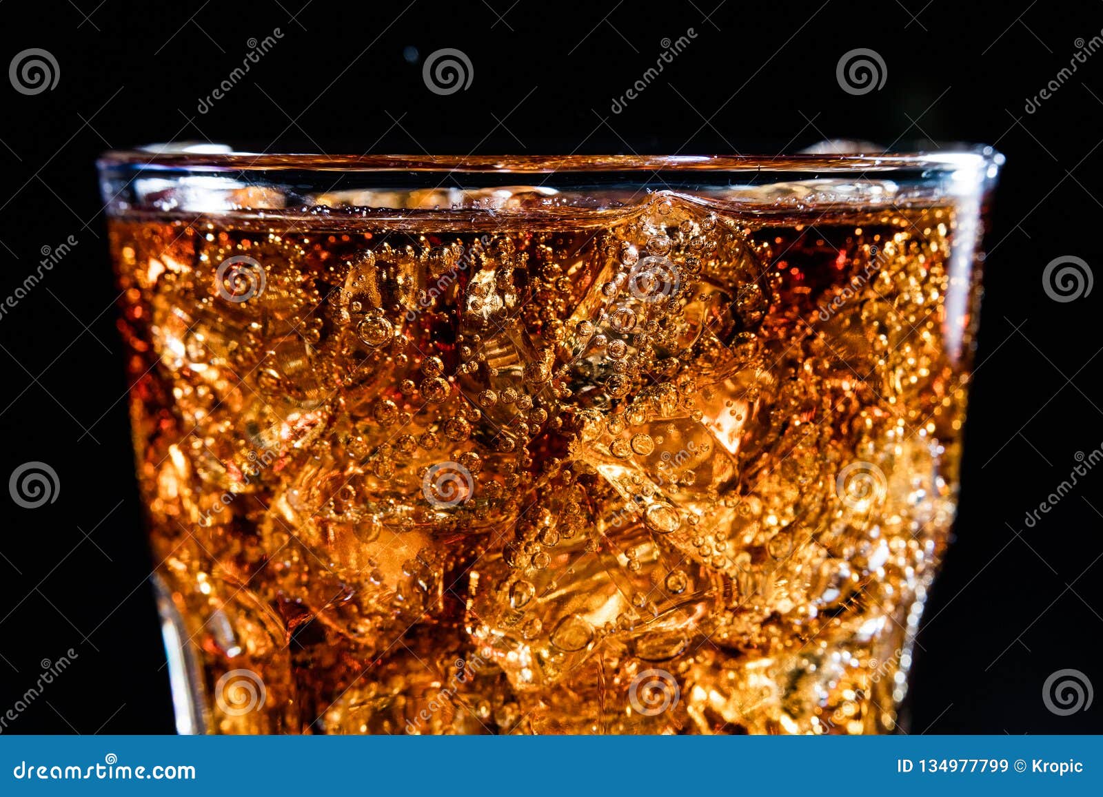 glass with soft cola drink, ice and bubles