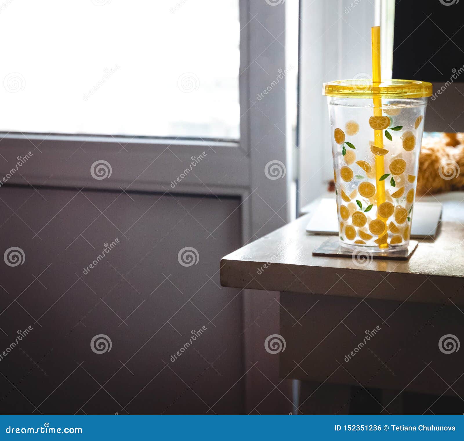 A Glass With A Straw With Painted Lemons On The Desk Of The Home