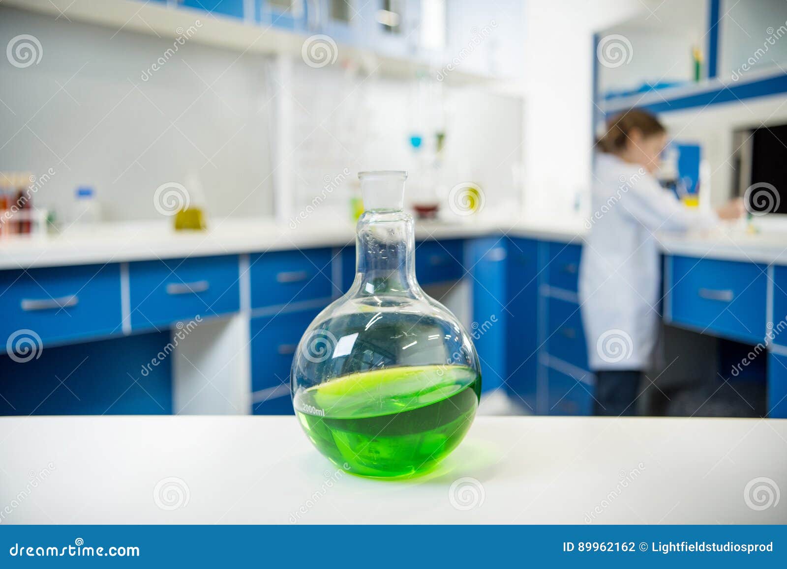 Glass Tube Wit Liquid on Lab Table with Scientist Behind Stock Photo