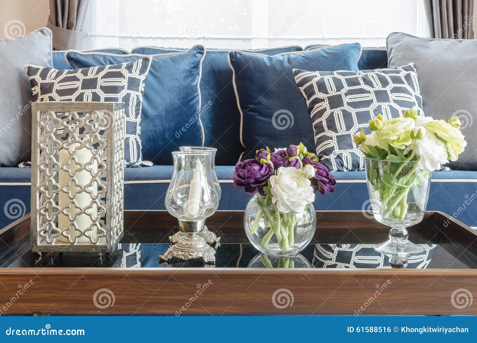 Glass vas av blomman på tabellen i vardagsrum med blå klassiker s ...
