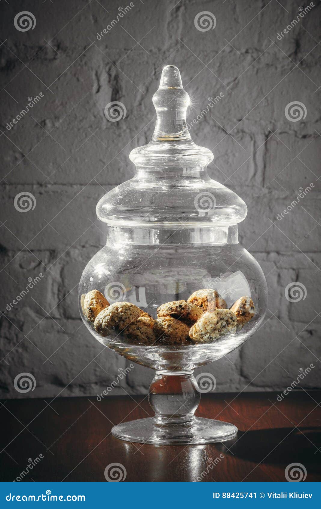 Glass Vase With Cookies And Cover On Desk Near Grey Wall Stock