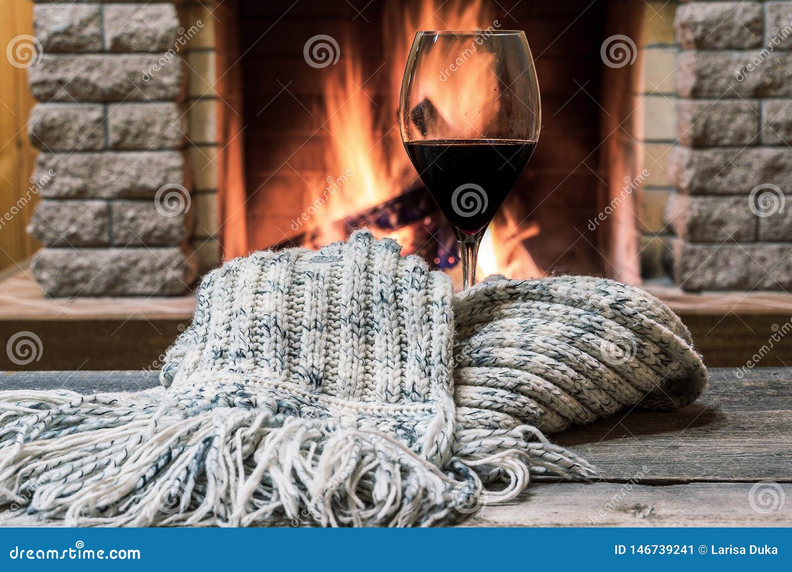 glass of wine against cozy fireplace background, hygge concept