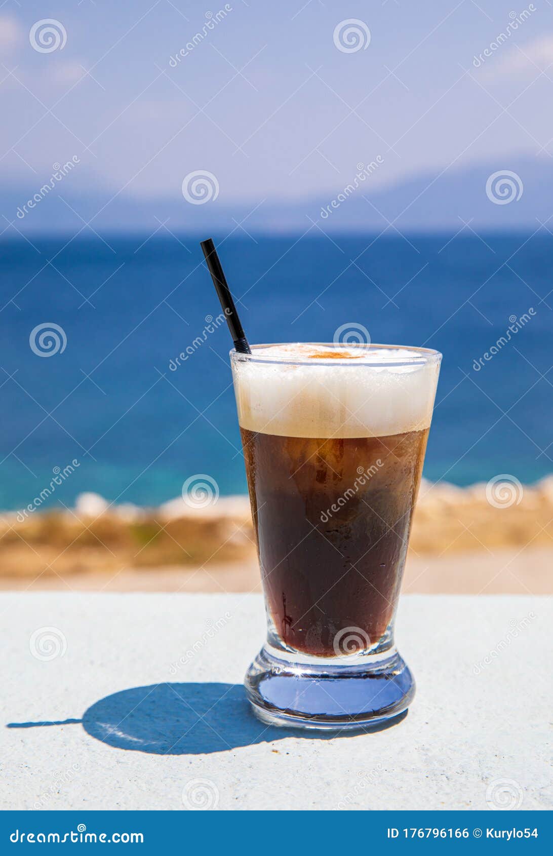 glass of yummy iced coffee or greek freddo cappuccino on the seascape background on a summer sunny day in kastos island