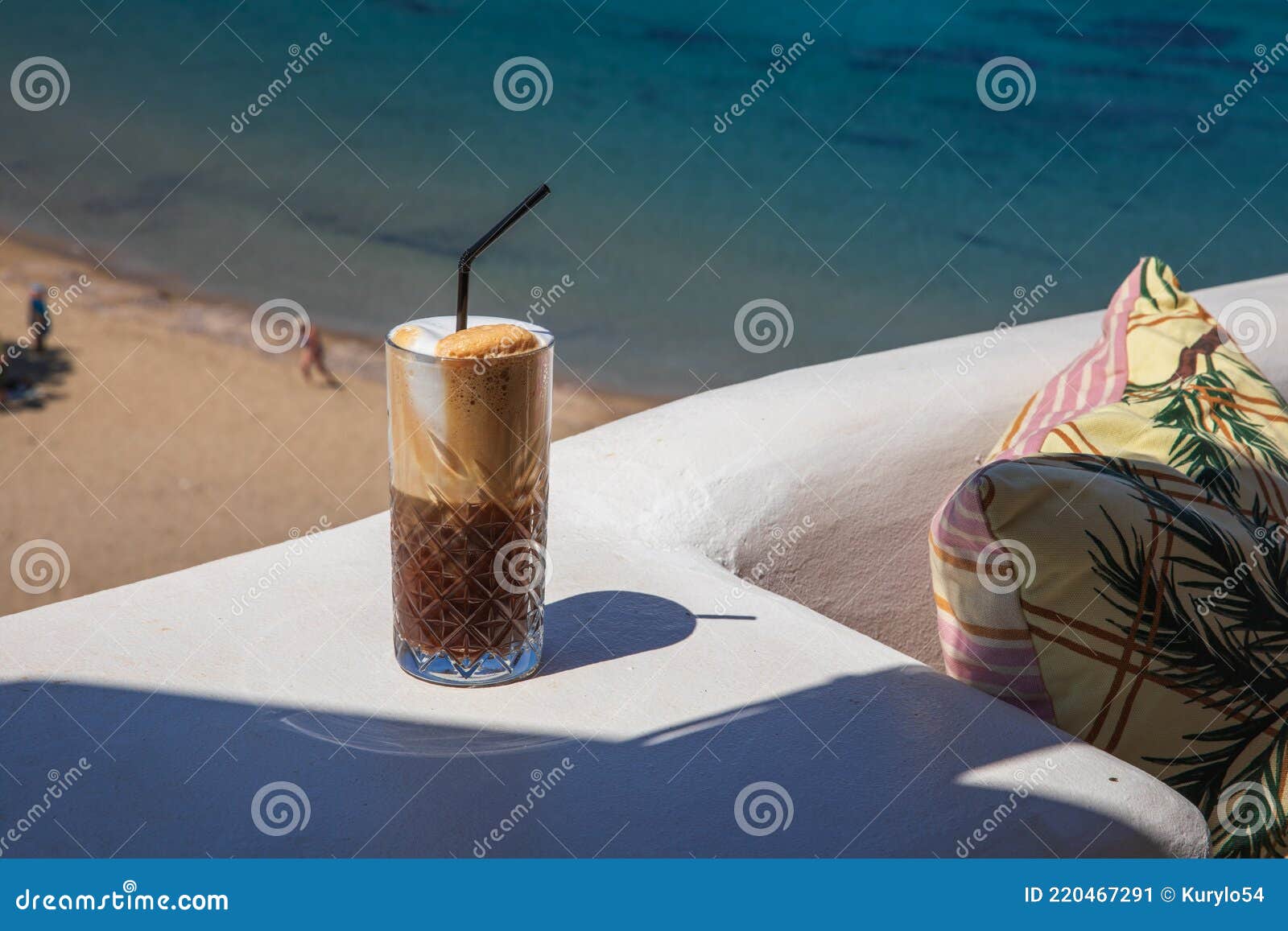 glass of yummy iced coffee or greek freddo cappuccino on the seascape background on a summer sunny day at the kythnos