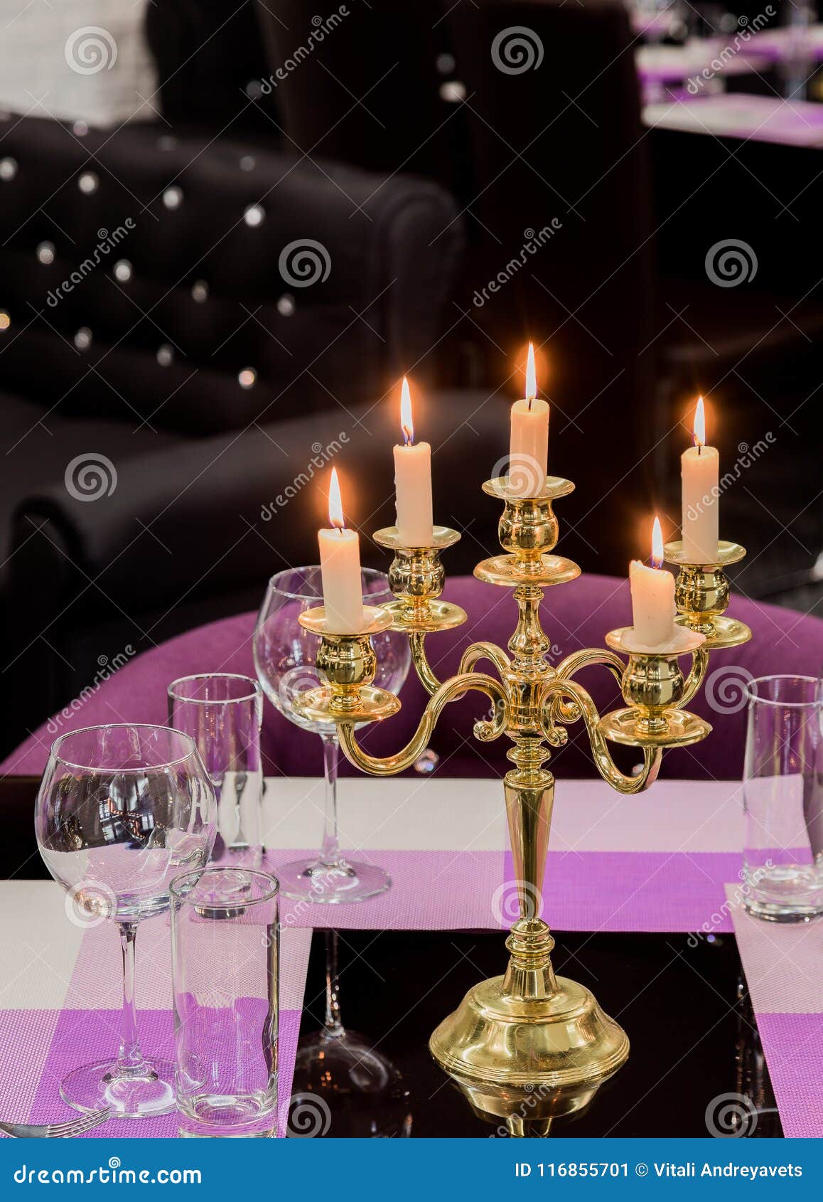 Glasses and a Candlestick on a Glass Table in a Restaurant. Romantic