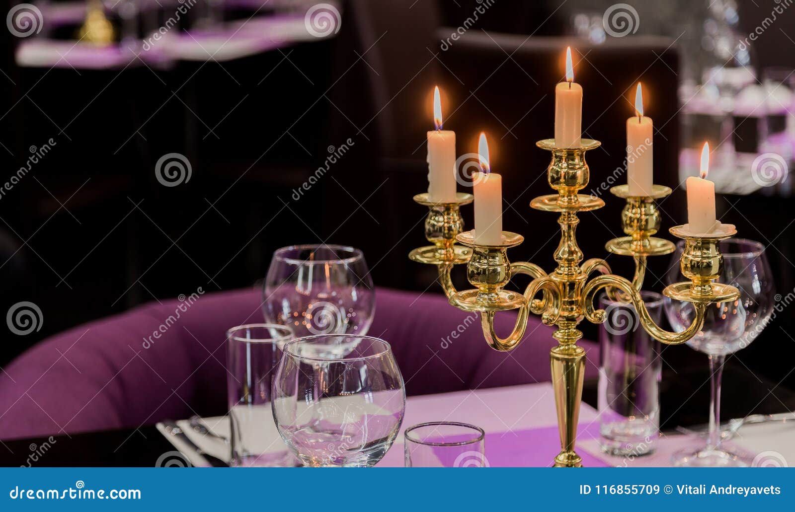 Glasses and a Candlestick on a Glass Table in a Restaurant. Romantic