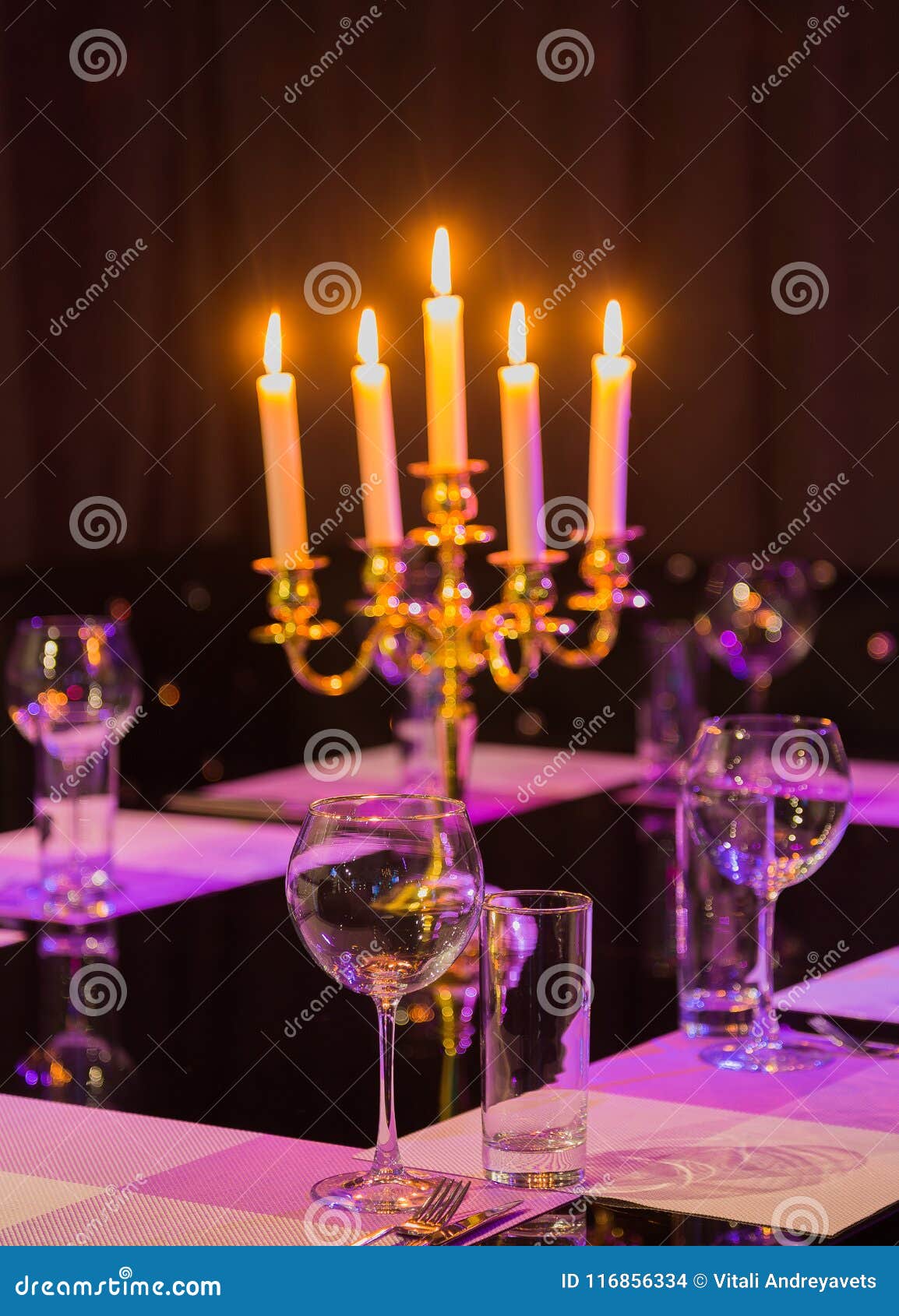 Glasses and a Candlestick on a Glass Table in a Restaurant. Romantic