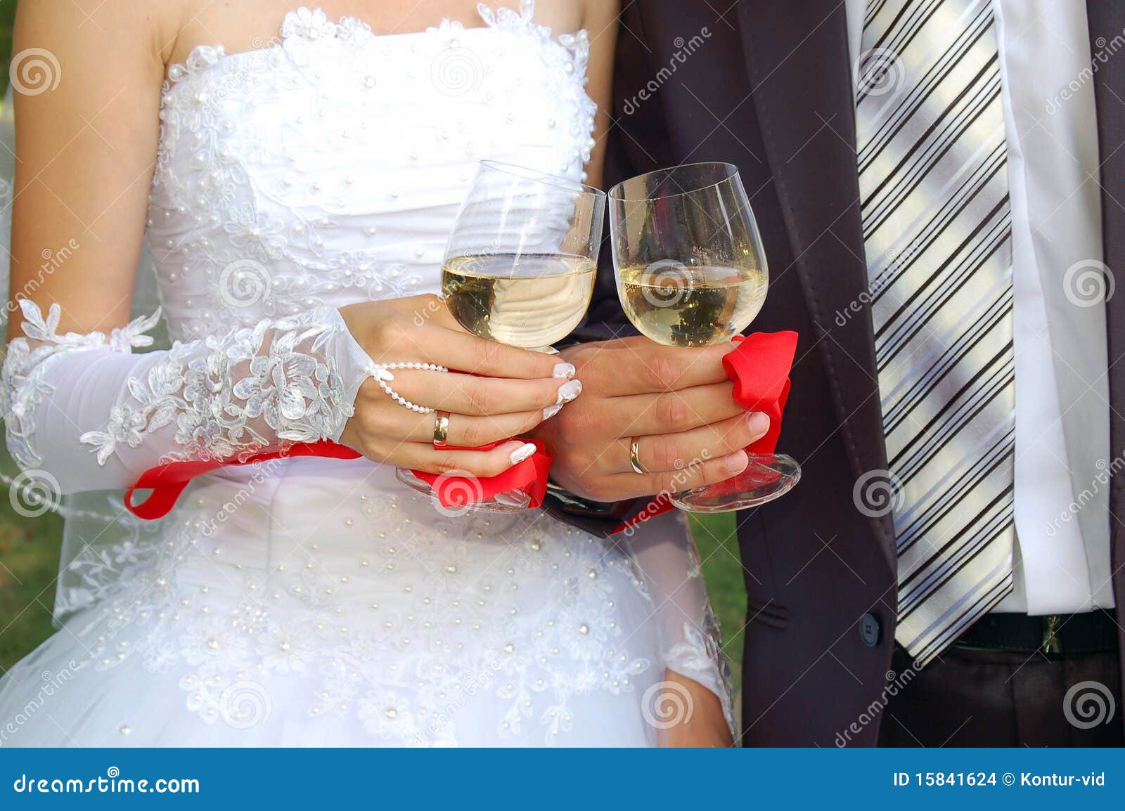 glasses in the hands of groom and fiancee
