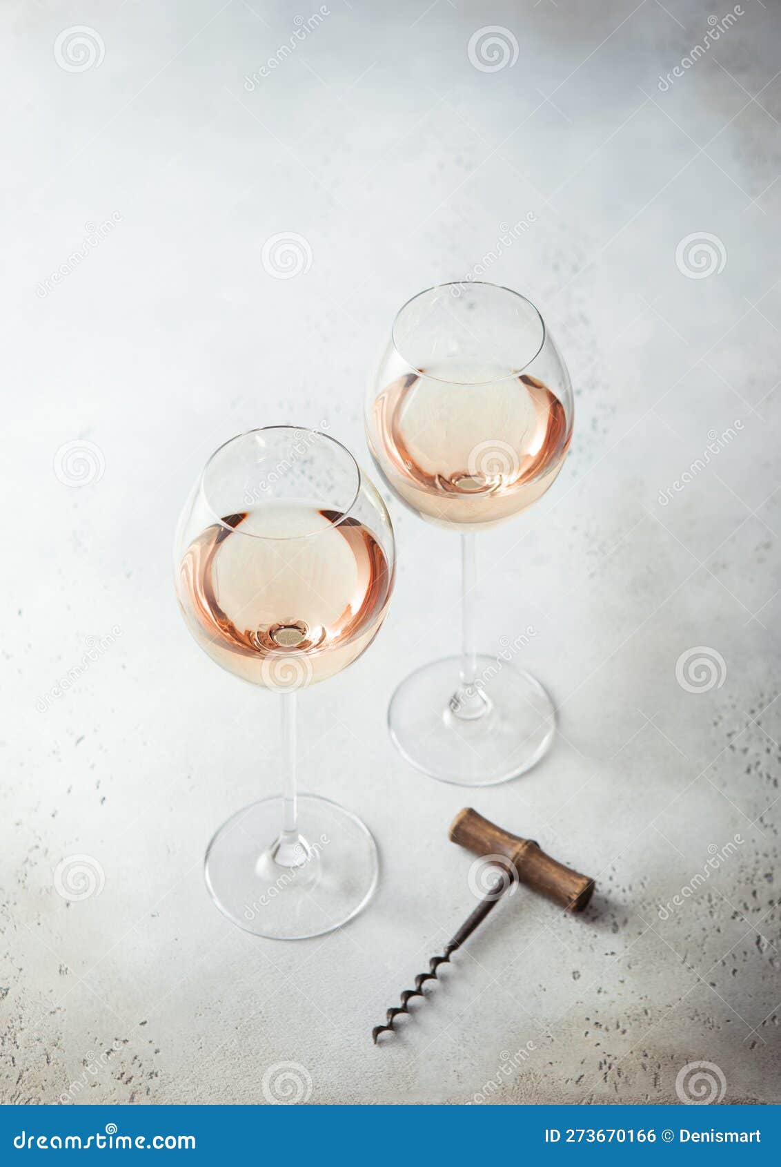 Glasses of Pink Rose Wine and Vintage Corkscrew on Light Background