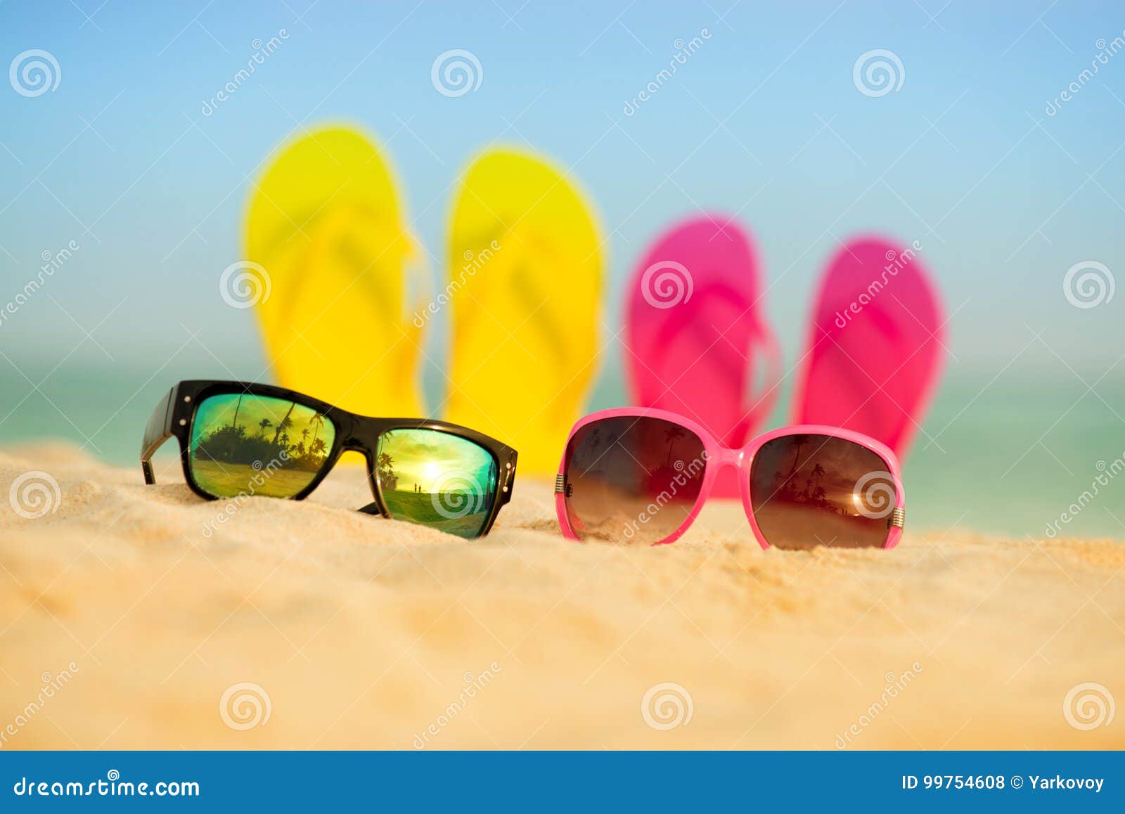 Glasses With Yellow And Pink Sandals Stand In The Sand Against The ...