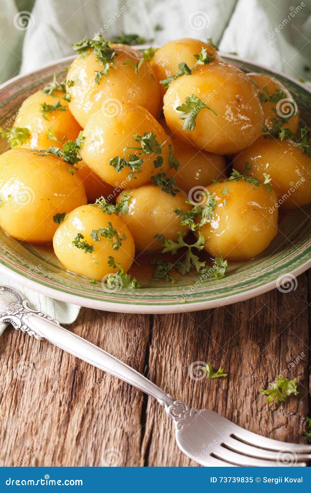 Glazed New Potatoes with Parsley Closeup on the Table. Vertical Stock
