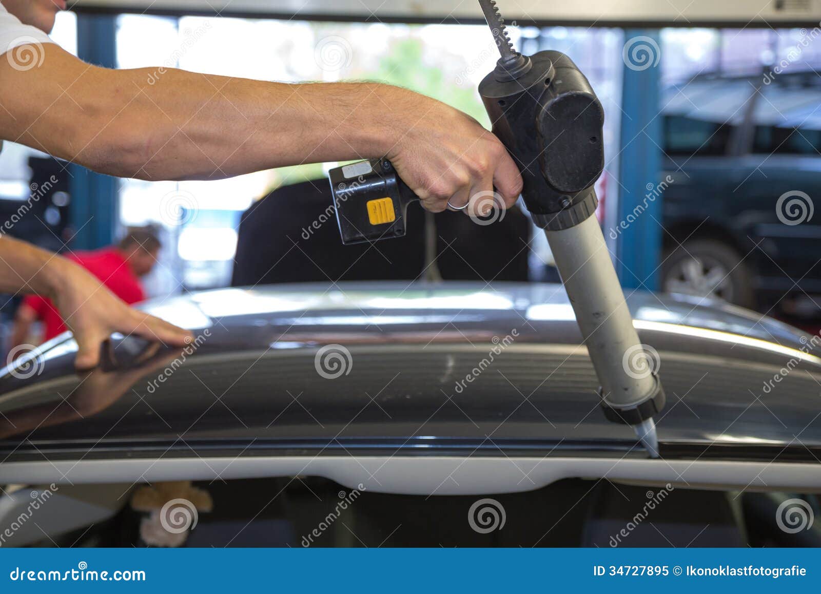 Glazier with Application Gun in Garage Replacing Windshield or