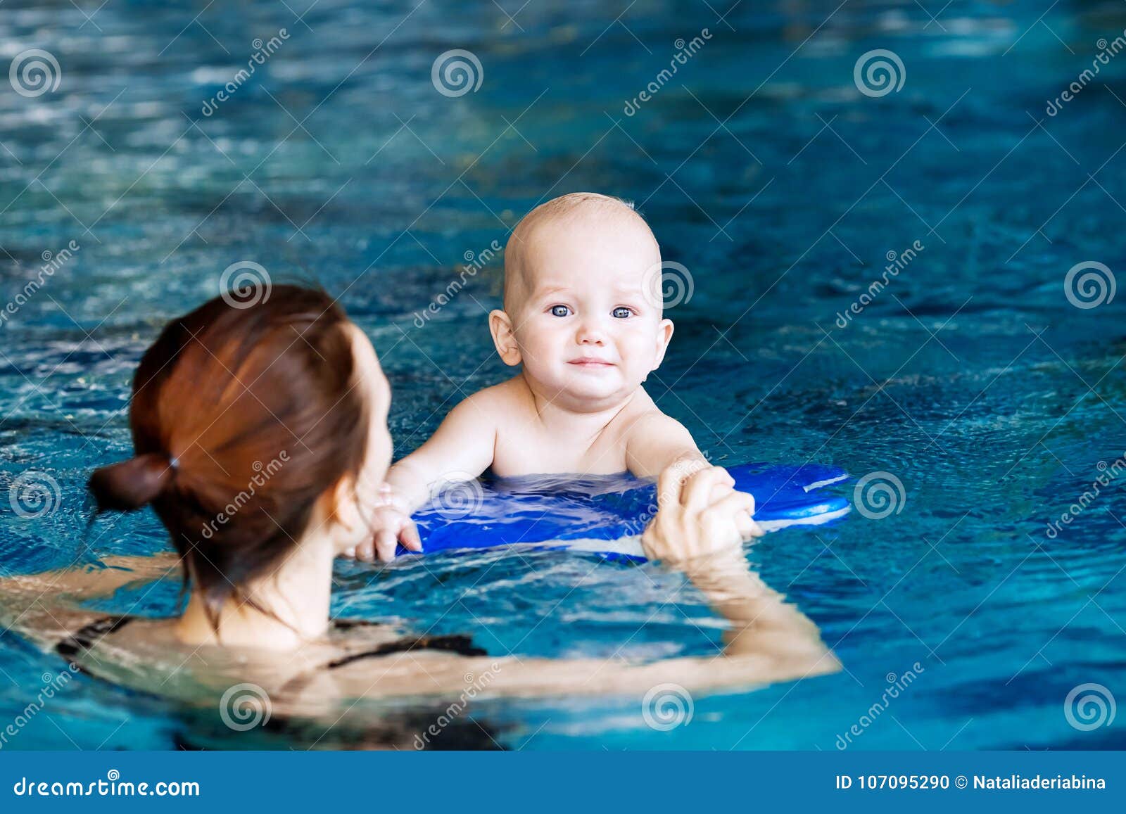 Glimlachende charmante baby in zwembad. De baby van het moederonderwijs om te zwemmen Portret van charmante 11 maanden kind in het klaslokaal in een zwembad Gezond Gezinsleven