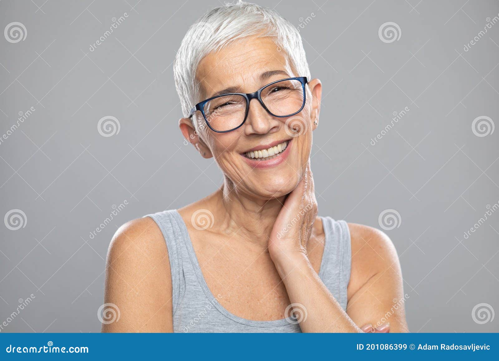 Glimlachende Oudere Vrouw Met Grijs Haar En Een Bril Die Voor De Achtergrond Poseren Stock Afbeelding - Image haar, stellen: