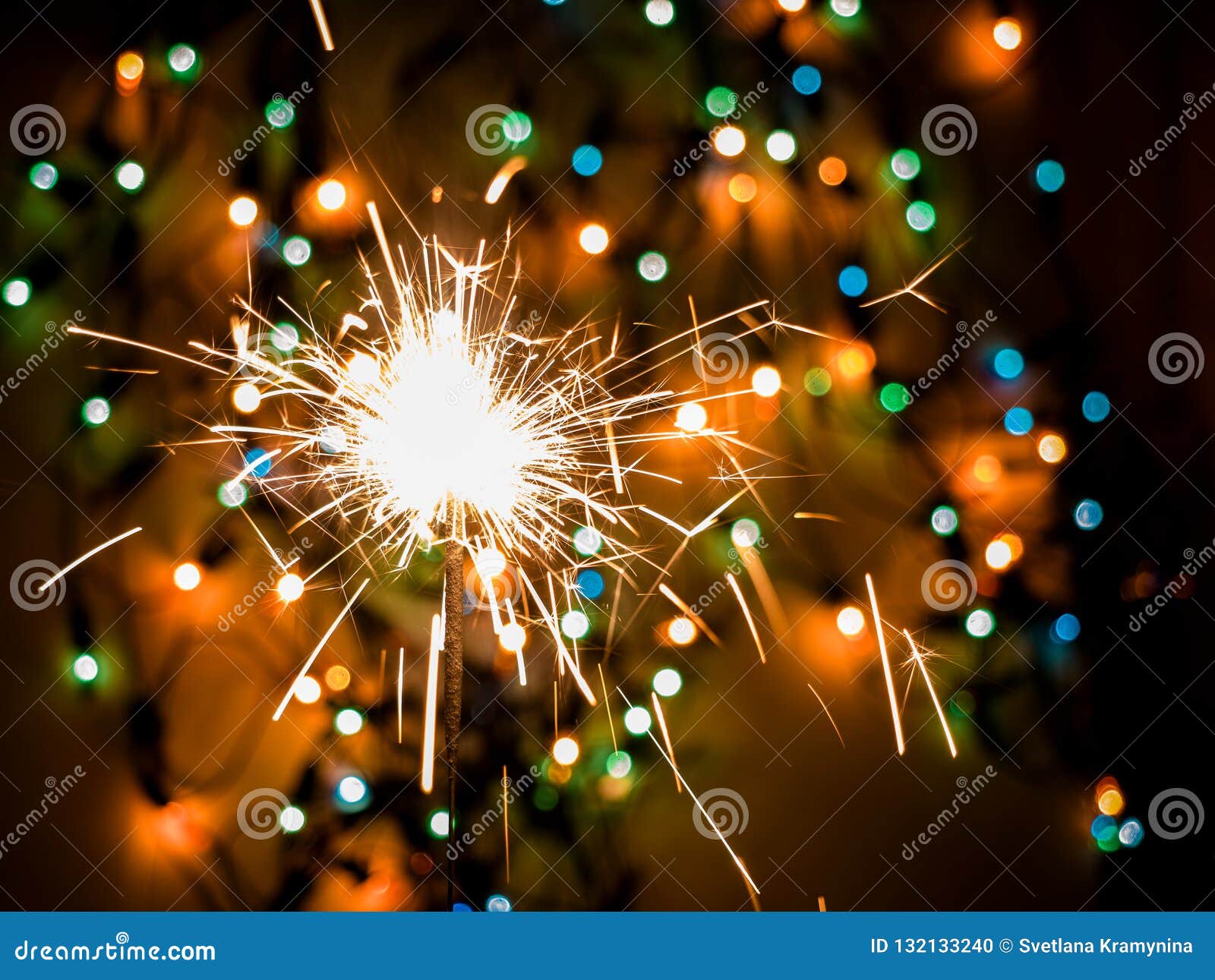 Glittering Burning Sparkler on Colorful Bokeh Background. Stock Photo