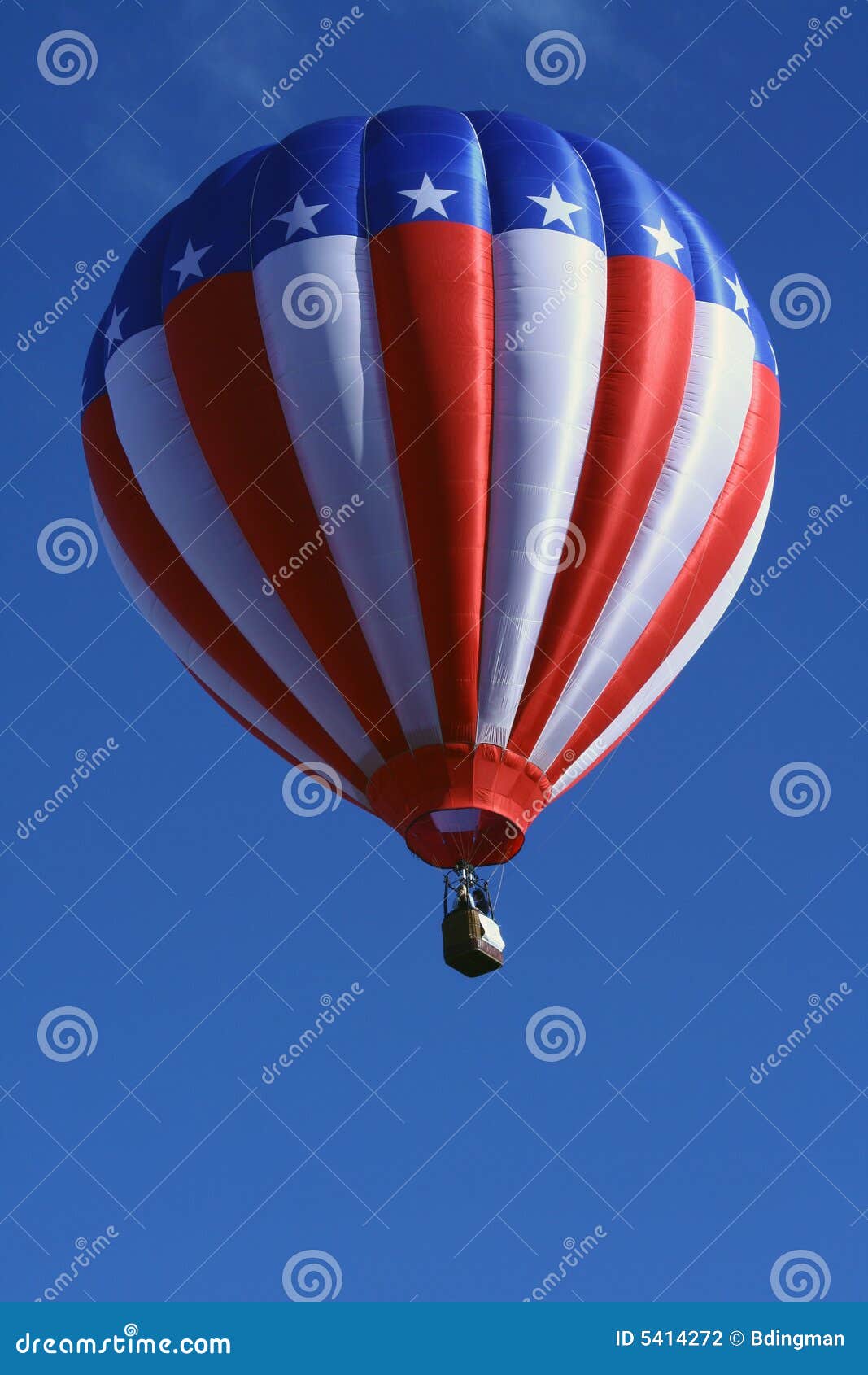 Globo patriótico del aire caliente. Un globo rojo, blanco y azul del aire caliente flota en un cielo azul profundo.