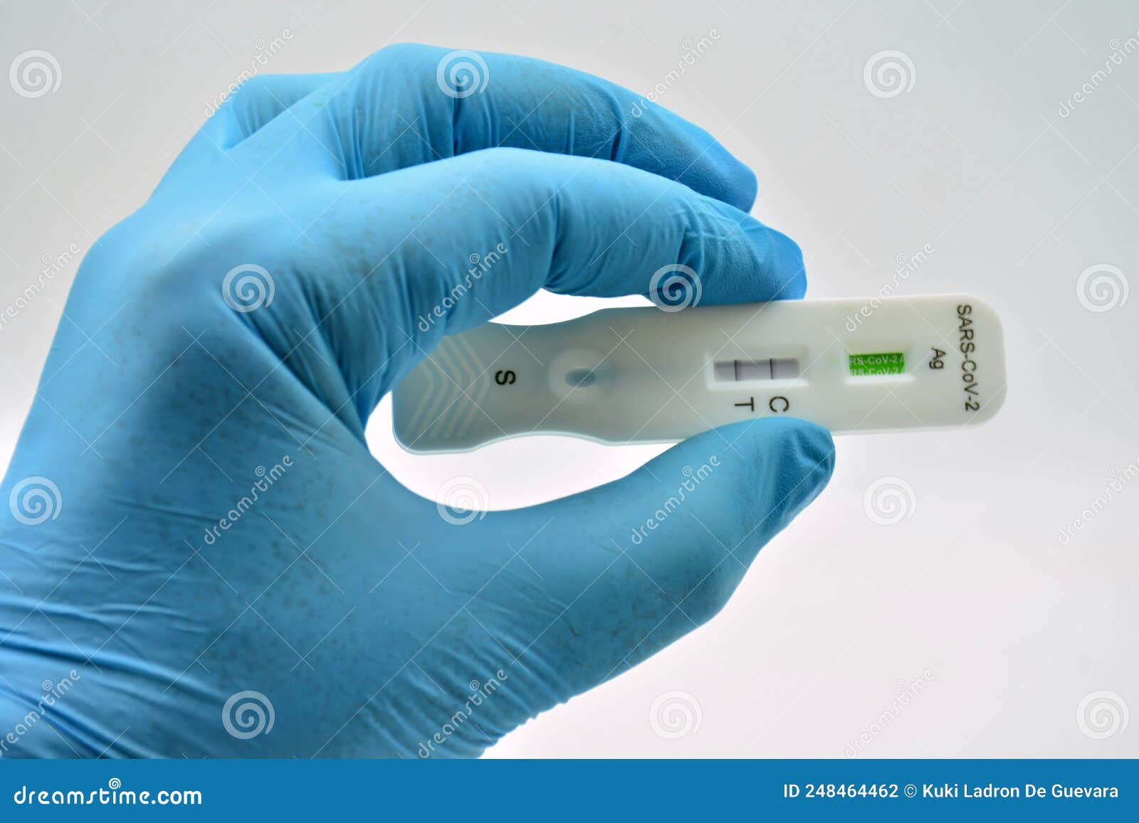 gloved hand holding an antigen test