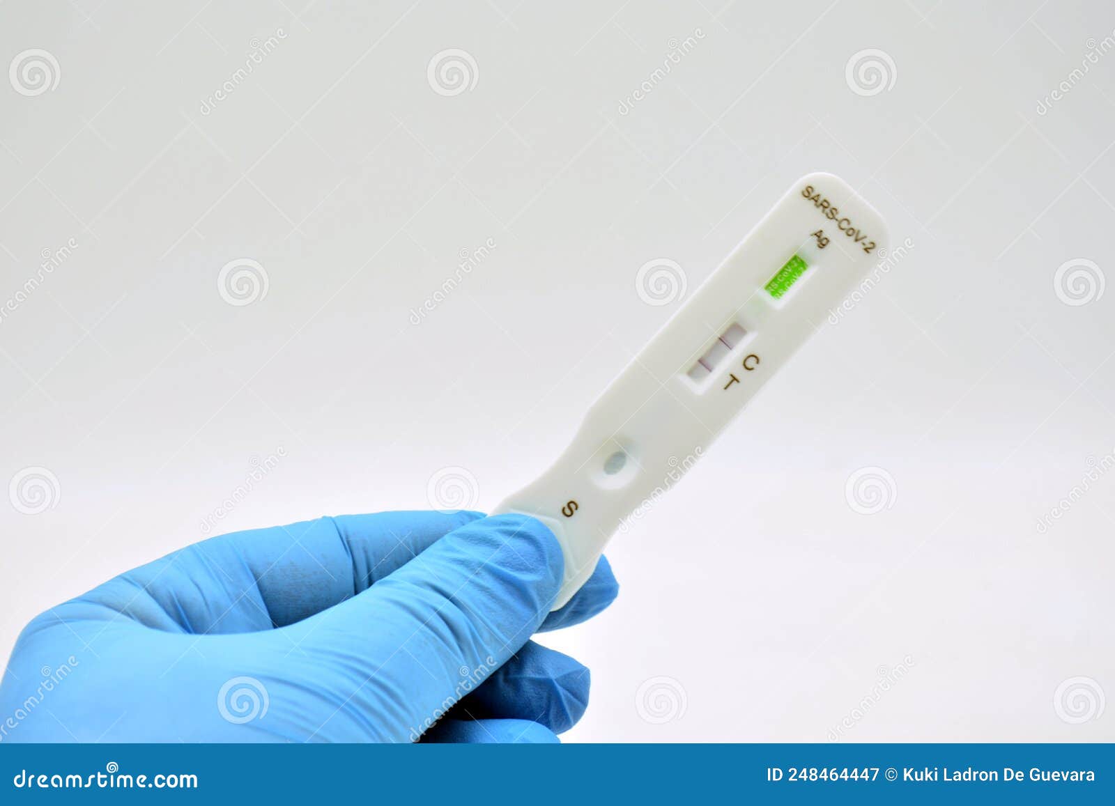 gloved hand holding an antigen test