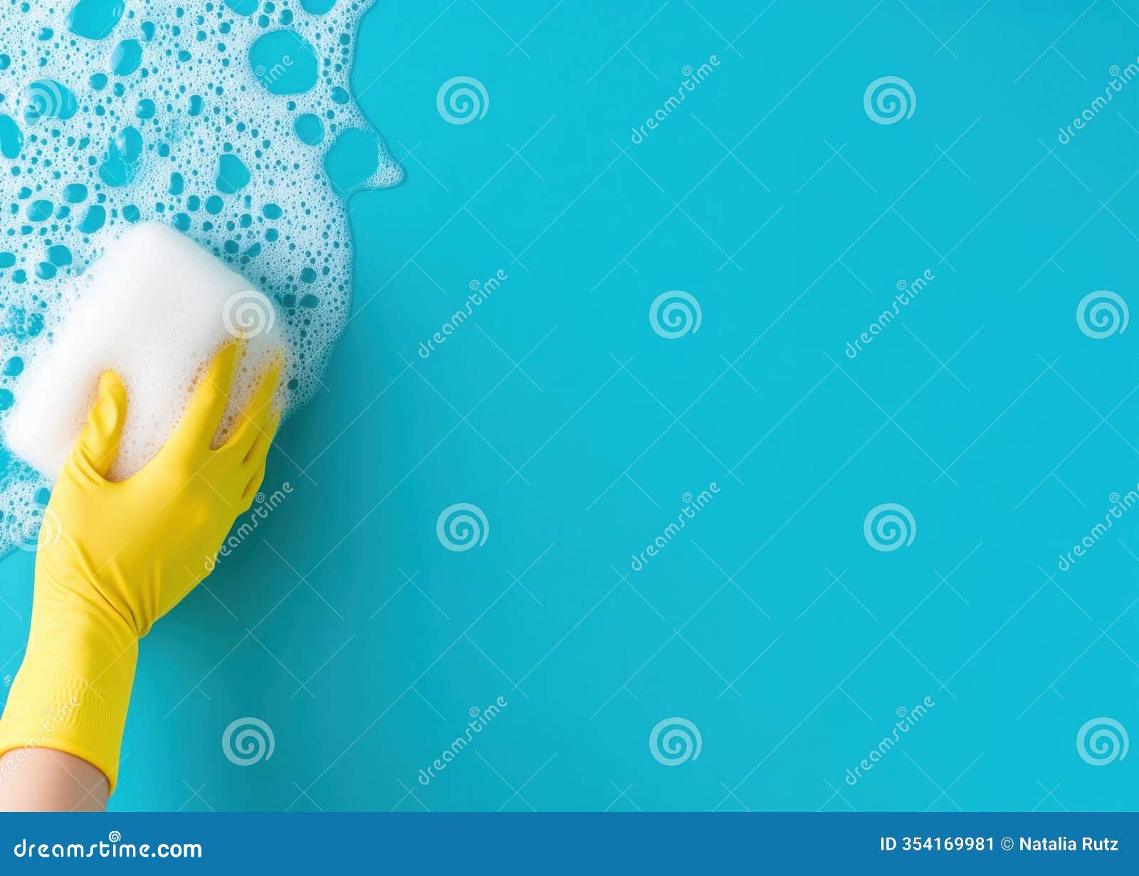 gloved hand holding a foam-filled sponge on a bright blue surface during a cleaning activity
