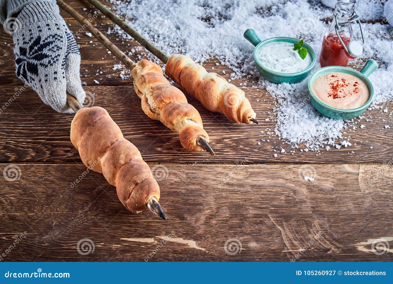 gloved hand holding a skewer of twist bread