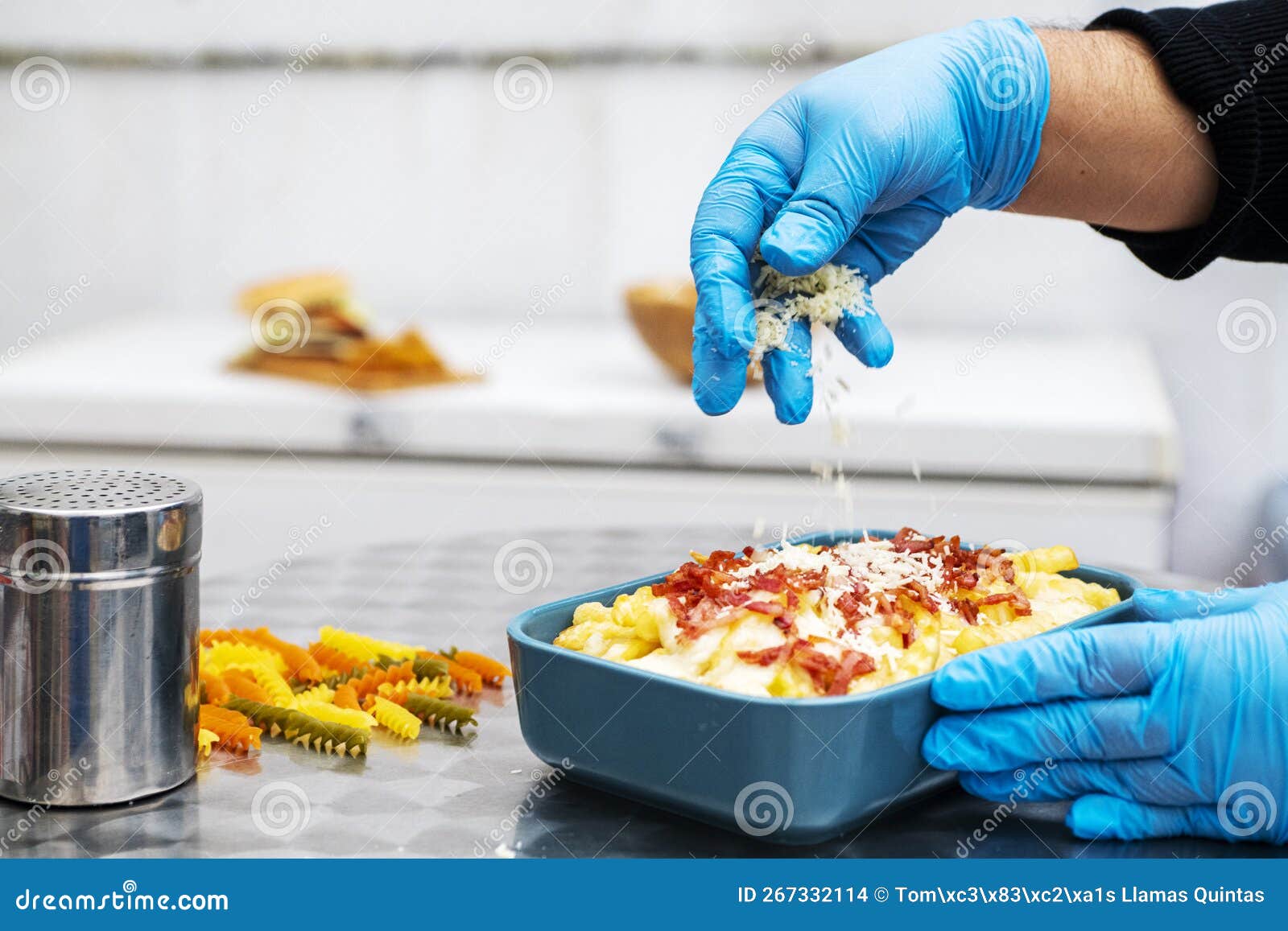Gloved Hands of a Chef Preparing a Bowl of Bacon Chips with Cheese