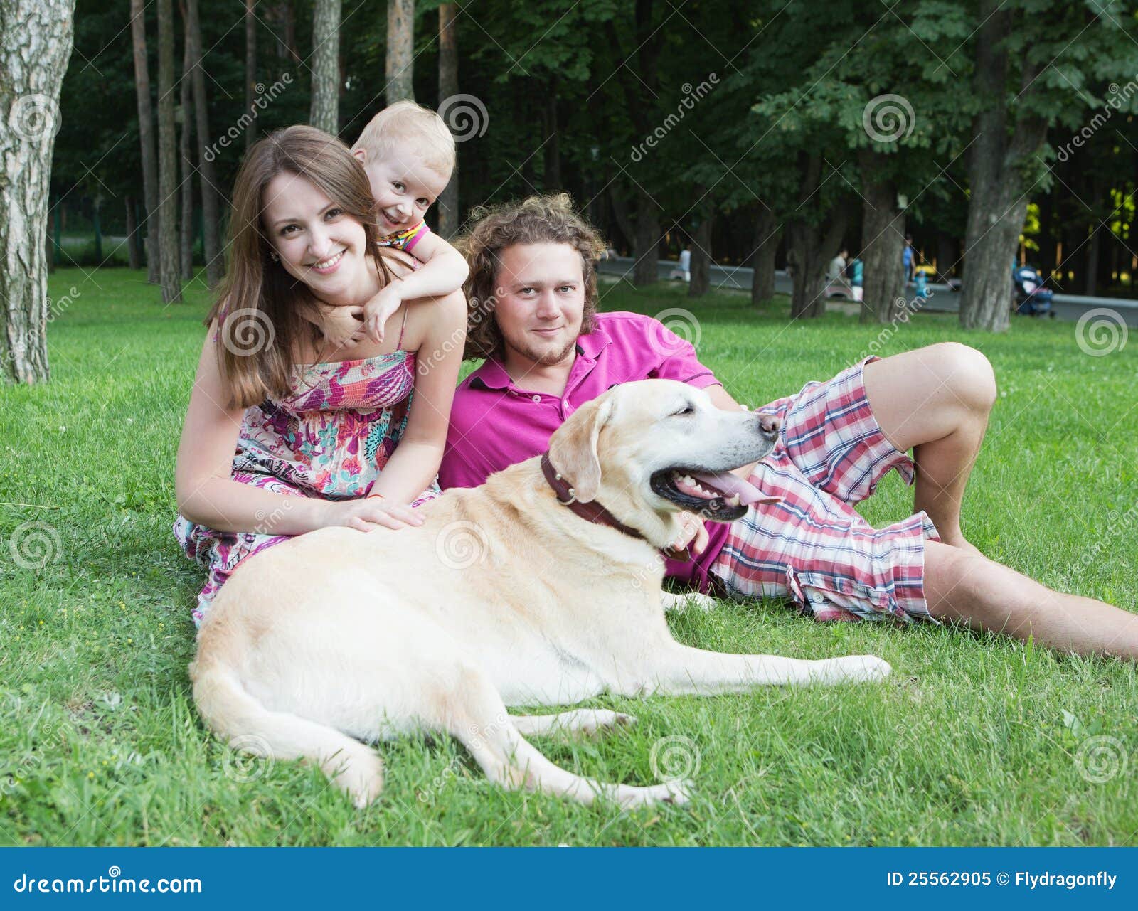 Glückliche Familie im Park. Glückliche junge Familie mit Hund steht im Park still