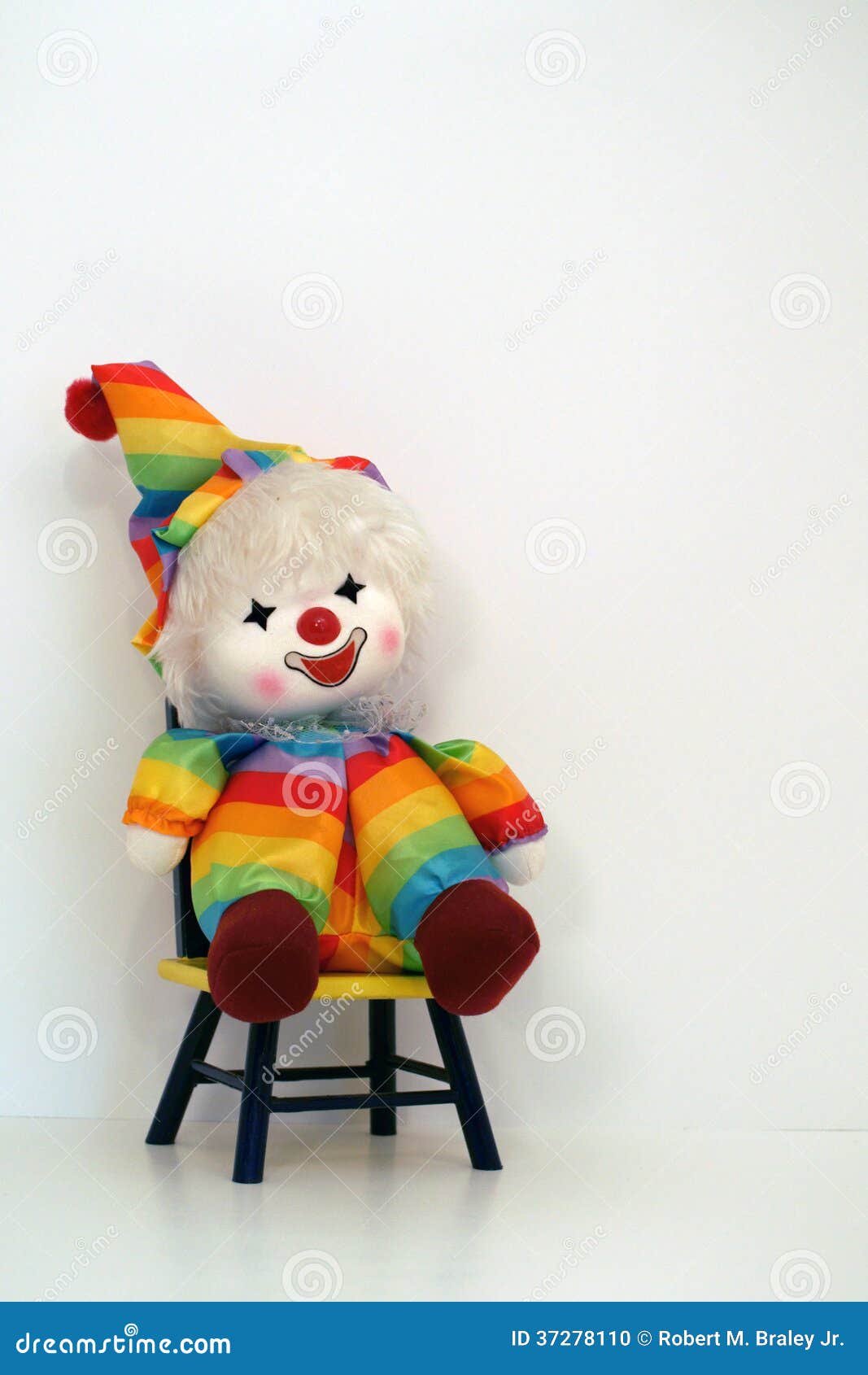 Glückliche gegenübergestellte Clownpuppe, die auf einem TIMEOUTstuhl sitzt