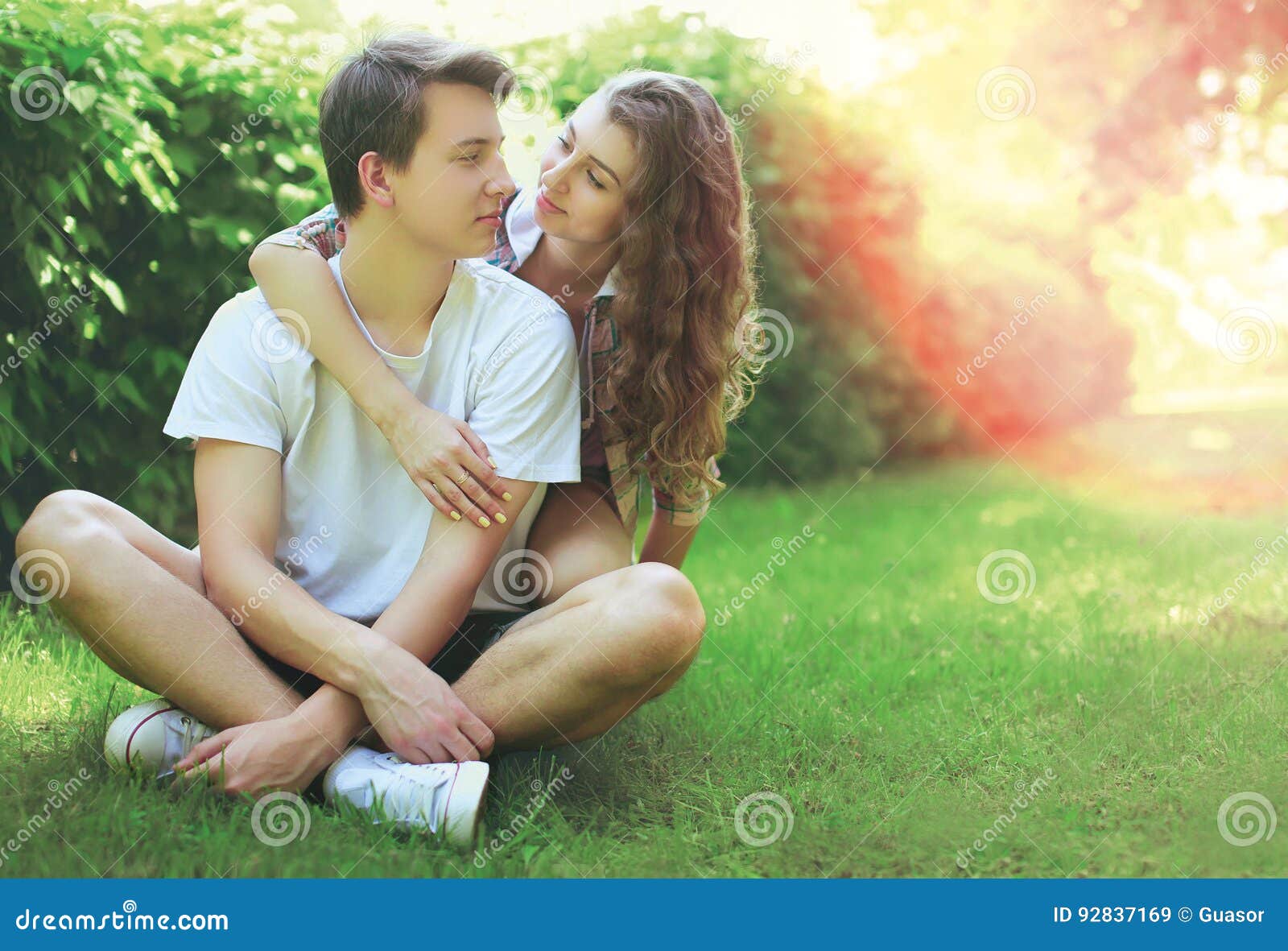 Glückliche Süße Junge Paarjugendliche Die Auf Dem Gras Im Sommer Sitzen Stockbild Bild Von