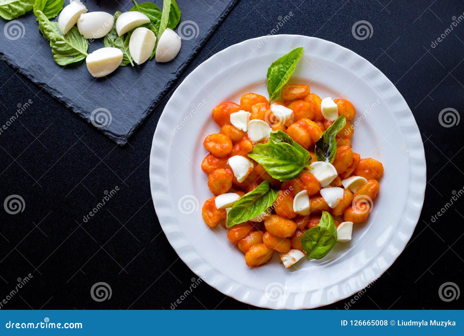 gnocchi alla sorrentina in tomato sauce with green fresh basil and mozzarella balls served on a plate