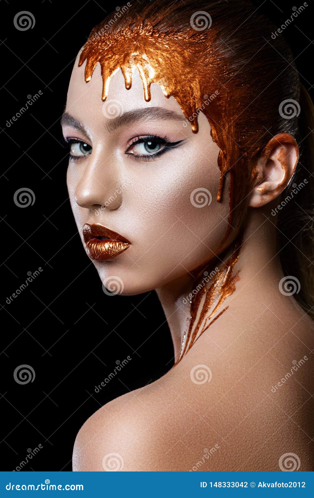 gold colors flow down from the lips, face and neck of a beautiful model girl, creative abstract makeup.
