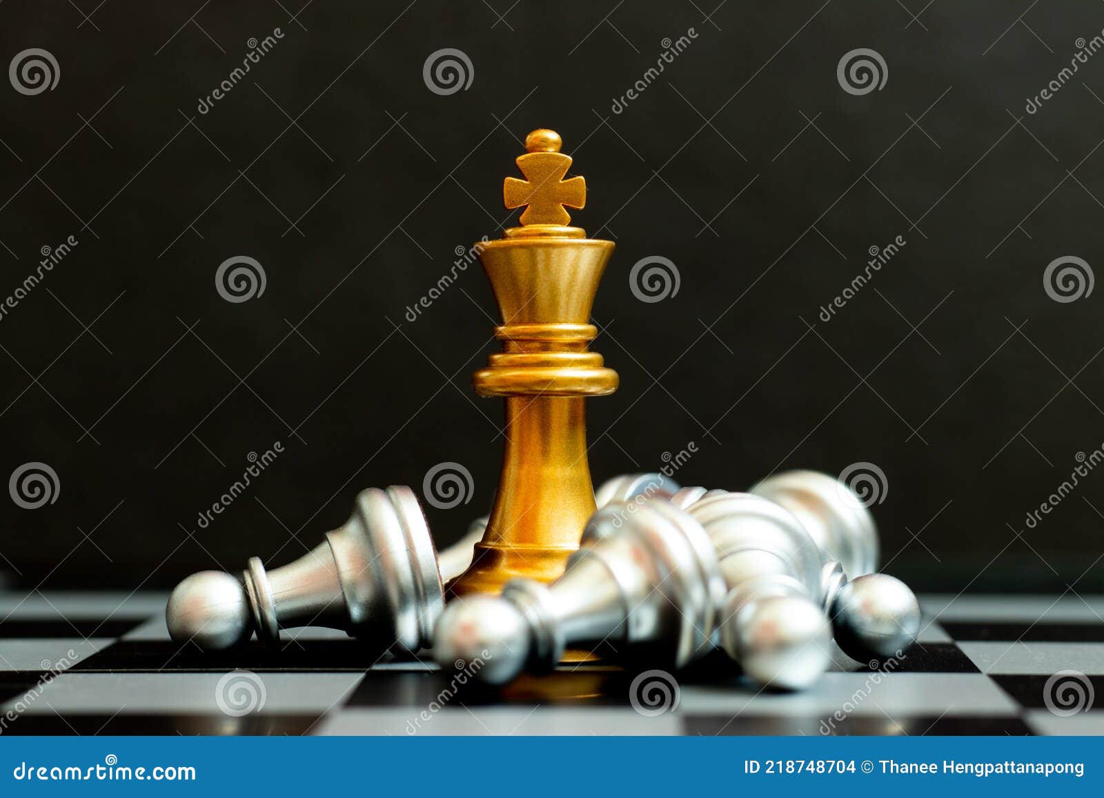 Gold king chess piece win over lying down pawn on black background