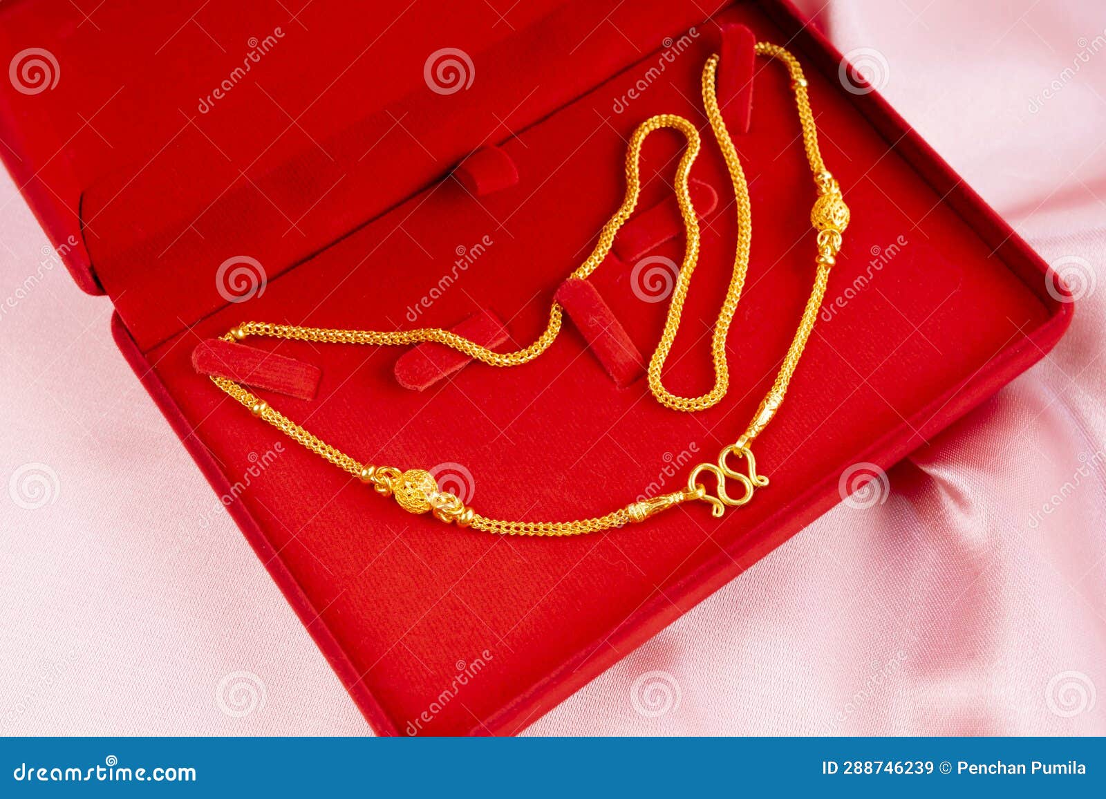 The Gold Necklace in a Red Box on a Pink Fabric Background Stock Image
