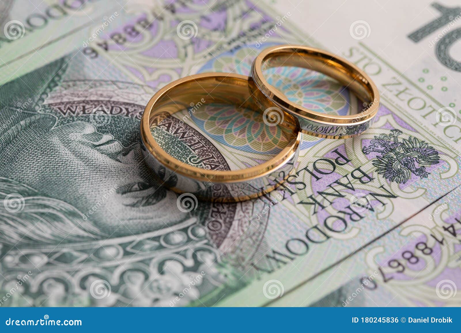 Gold Wedding Rings Surrounded by a Stack of Polish Banknotes Stock