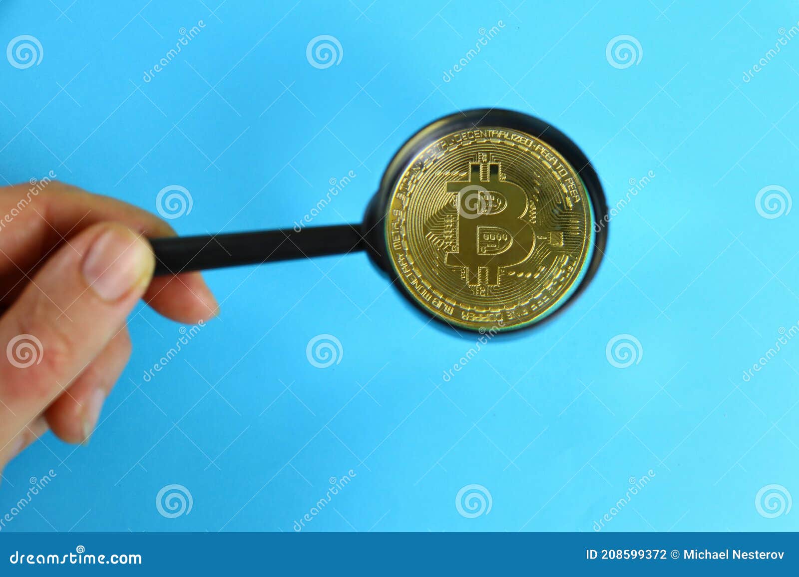 Magnifying glass with gold bar pile of gold coins under it Stock