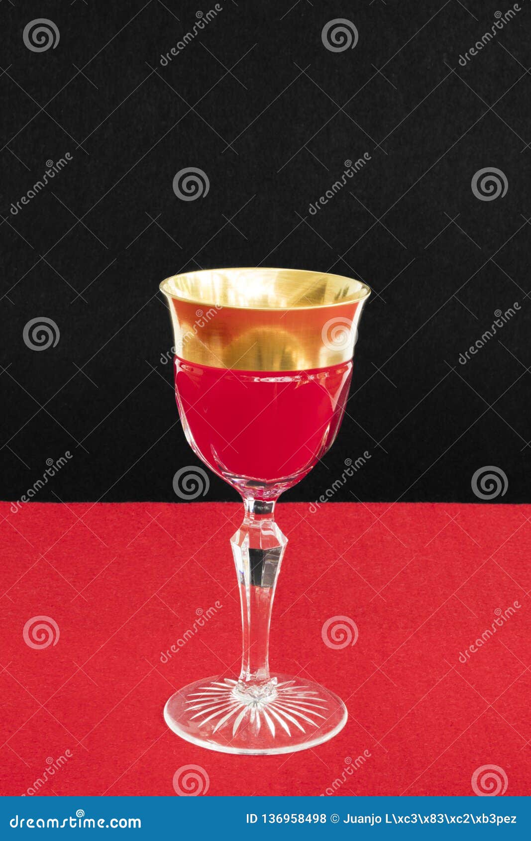 Golden Glass Filled with a Red Liquid in Red Black Background Stock